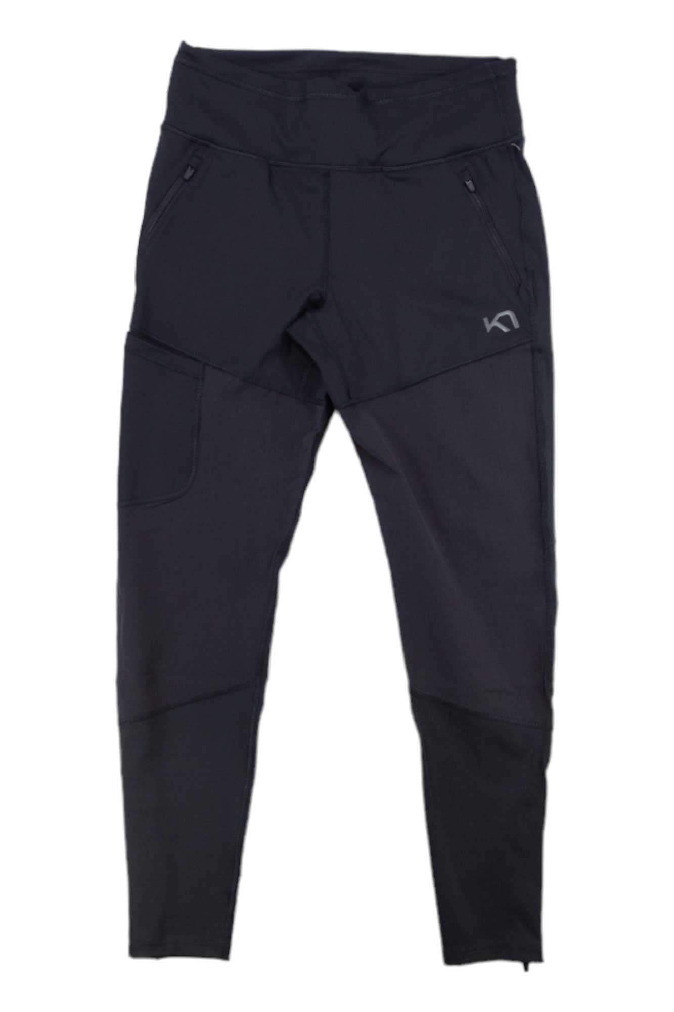 The Kari Traa Womens Sanne Tight is a pair of black athletic pants featuring 4-way stretch, zippered pockets, a small side pocket, and a subtle left-thigh logo. Shown laid flat on a white background.