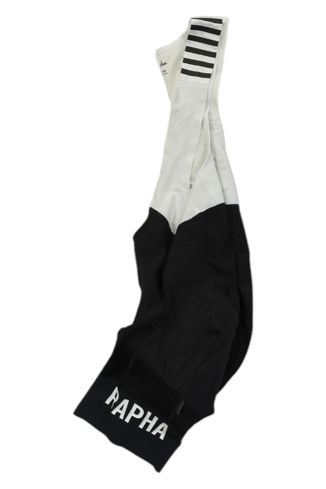 The Rapha Mens Pro Team Bib Shorts II - Regular features black and white design, RAPHA in white on the lower section, horizontal black stripes on the white shoulder straps, and a race-grade chamois for premium comfort.