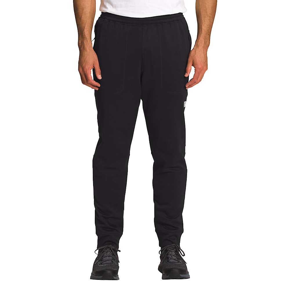 A person wearing The North Face Mens Canyonlands Jogger in black, paired with a white t-shirt and black athletic shoes, stands facing forward. Only the lower body is visible against a plain white background.