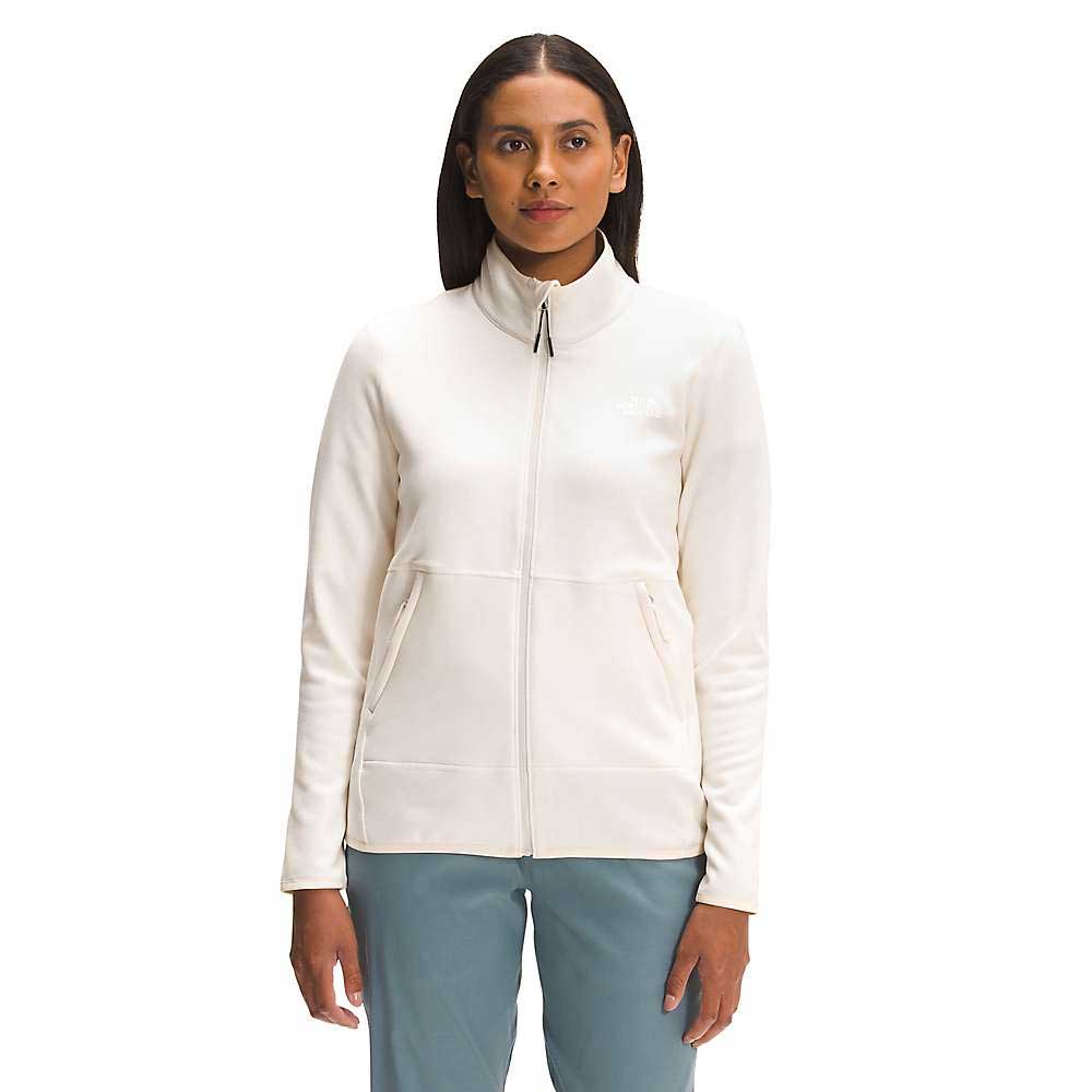 A woman stands facing forward in The North Face Women's Canyonlands Full Zip Jacket, a cream stretch fleece with a high collar, paired with blue pants against a plain white background.