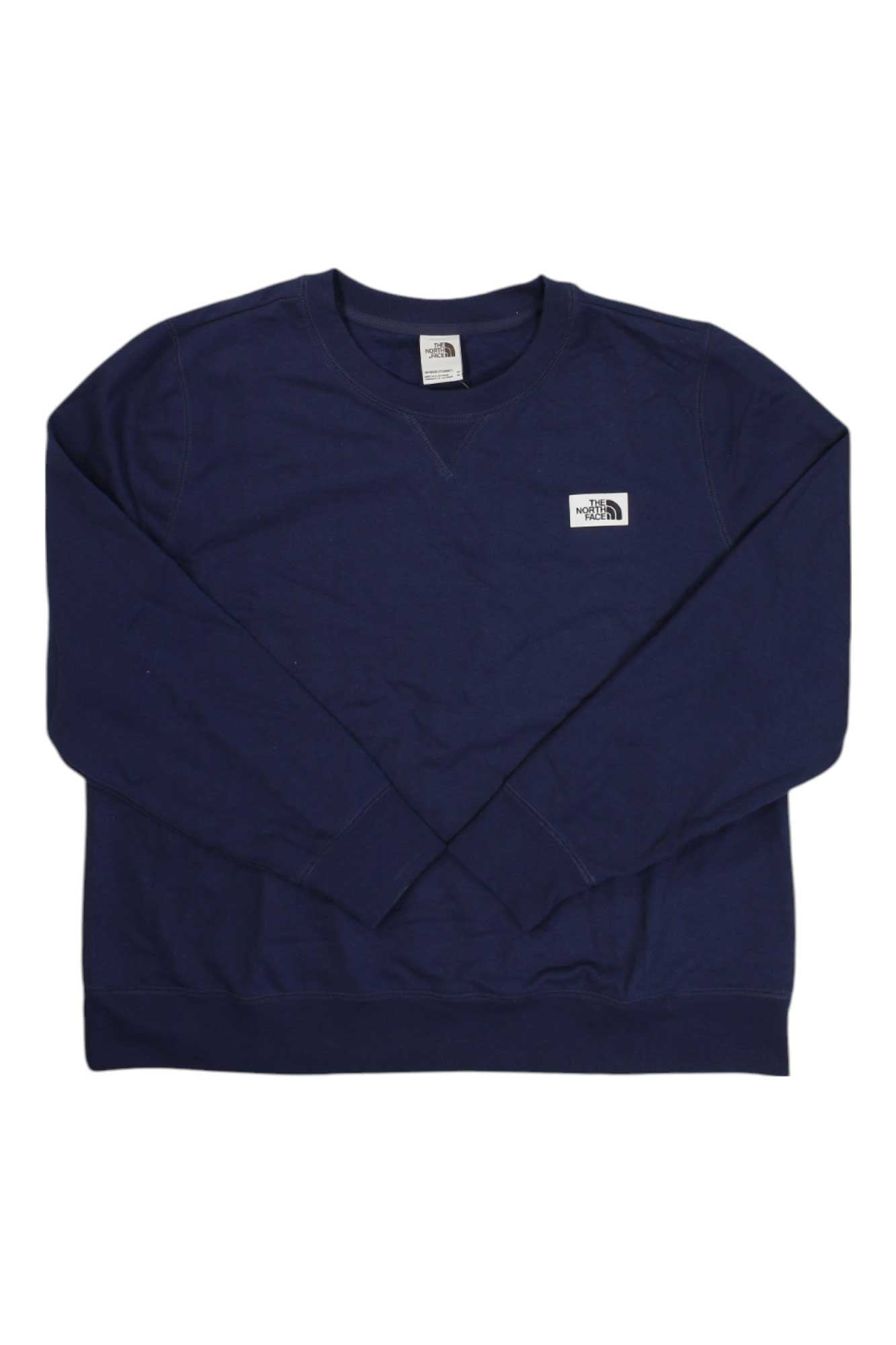 The North Face Womens Plus Heritage Patch Crew is a navy blue long sleeve sweatshirt with a small white logo patch on the left chest, designed for comfort as part of The North Face womens plus collection.
