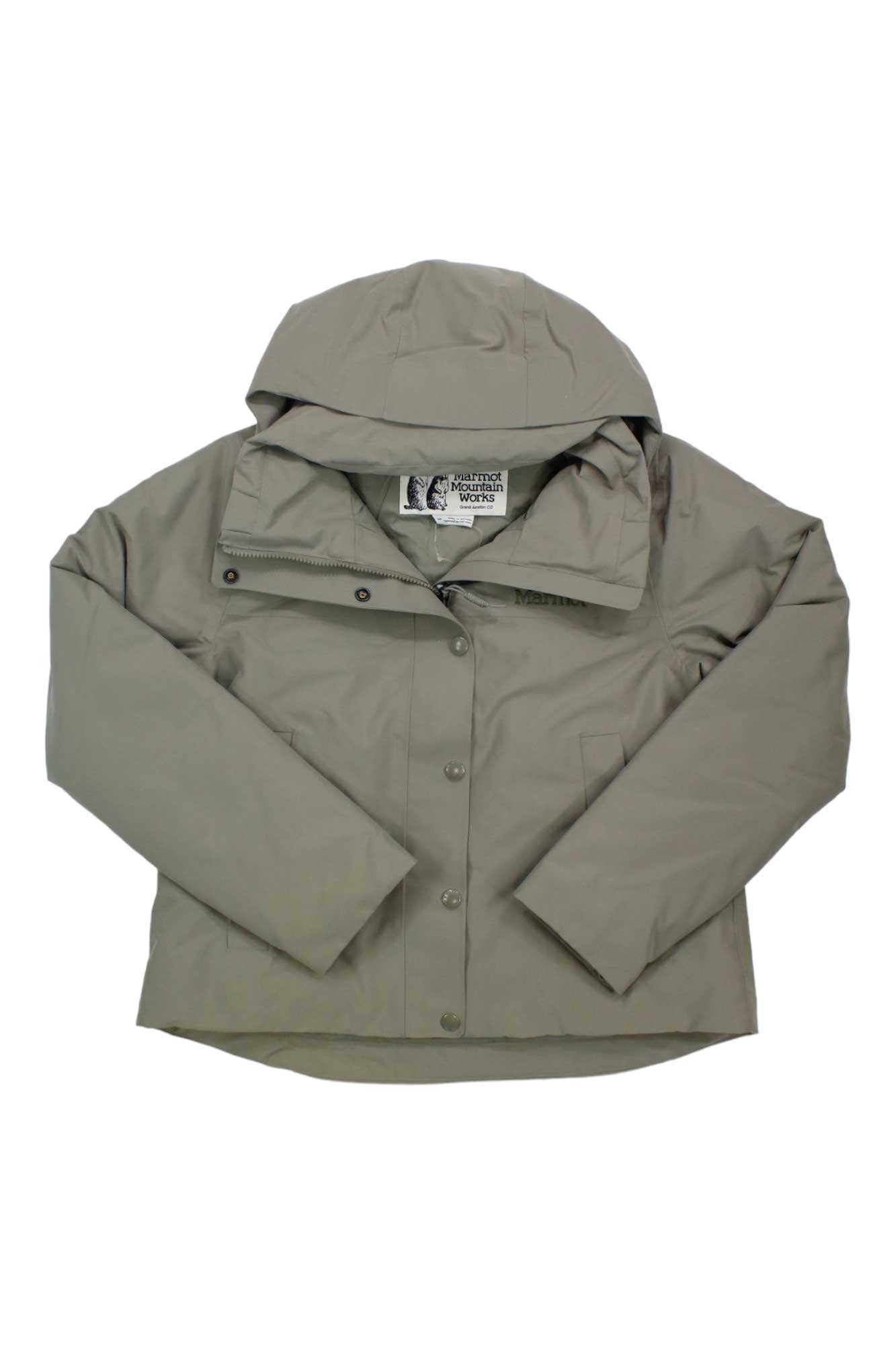 The Marmot Womens Chelsea Short Coat is a light gray, waterproof coat for women featuring long sleeves, button and zipper closure, and a visible clothing label inside the collar.