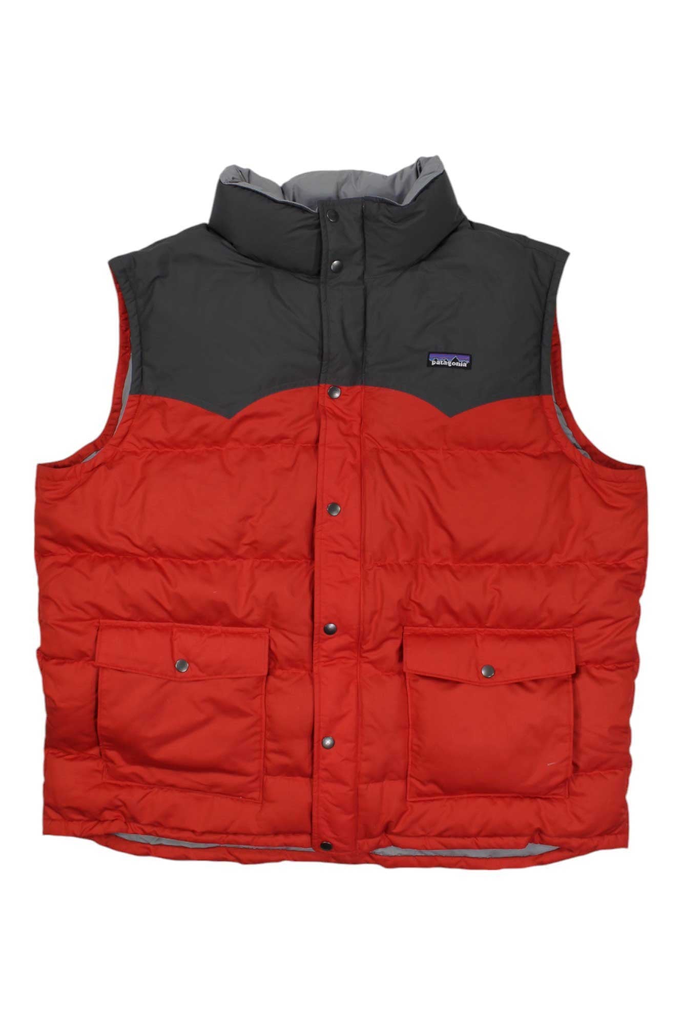 The Mens Slingshot Down Vest from Patagonia, in red and dark grey, features down insulation, two front pockets, snap buttons, and a high collar. Displayed against a plain white background.
