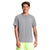 A smiling person in a light gray The North Face Mens Elevation SS Top made from recycled polyester and neon yellow shorts stands facing forward with arms relaxed, showing a right forearm tattoo—ready for any hiking adventure.