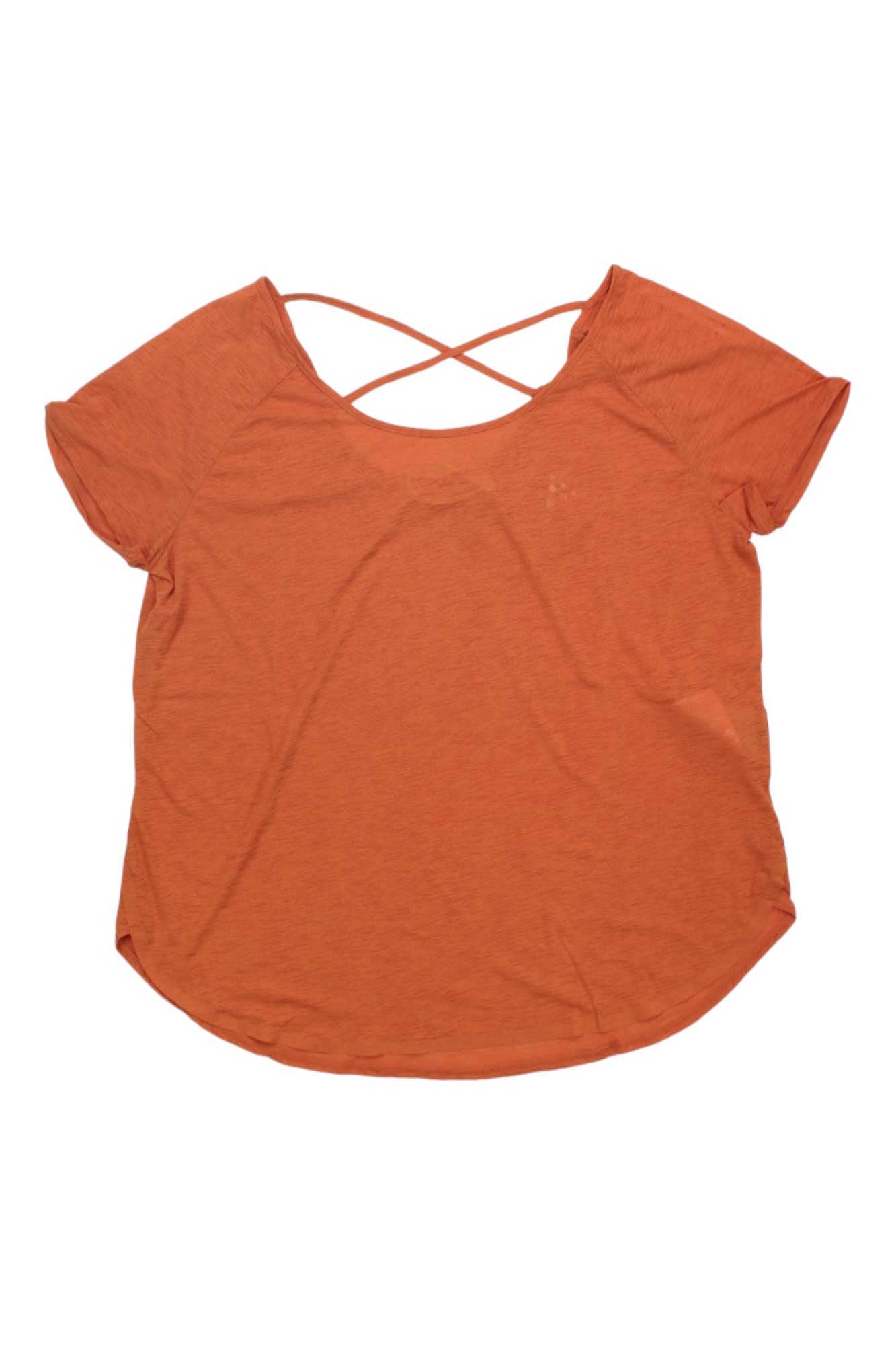 The Craft Sportswear Womens Core Charge Cross Back Tee is an orange, short-sleeve training top for women with a scoop neckline and crisscross strap detail on the back, shown laid flat on a white background.