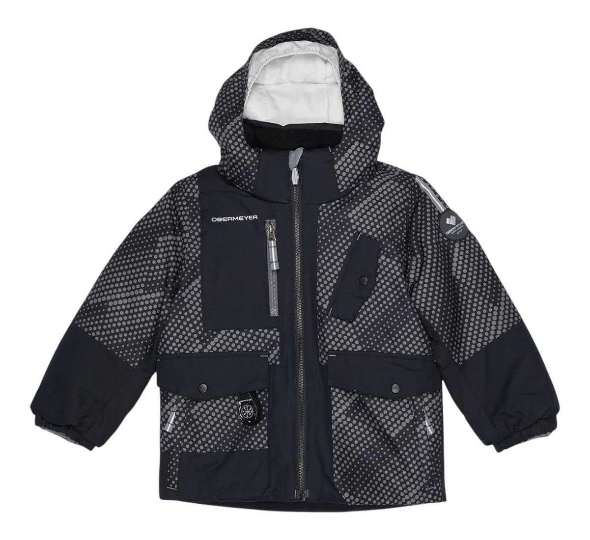 The Obermeyer Boys Nebula Jacket features a black and gray geometric dotted pattern, hood, front zipper, multiple pockets, and elastic cuffs. This insulated winter jacket keeps active boys warm and stylish through cold months.