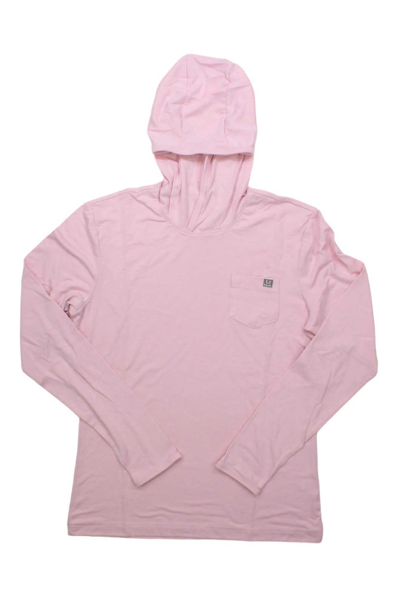 The Huk Womens Waypoint Hoodie is a light pink, long-sleeve fishing hoodie for women, made from recycled polyester. It features a front chest pocket with a small logo tag and is displayed laid flat on a white background.