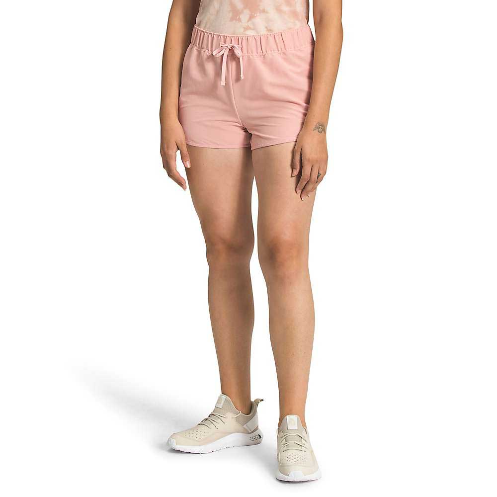 A person wears The North Face Womens Class V Mini 2.5 Inch Short in light pink with a tie-dye top and beige athletic shoes, photographed from the waist down against a plain white background.