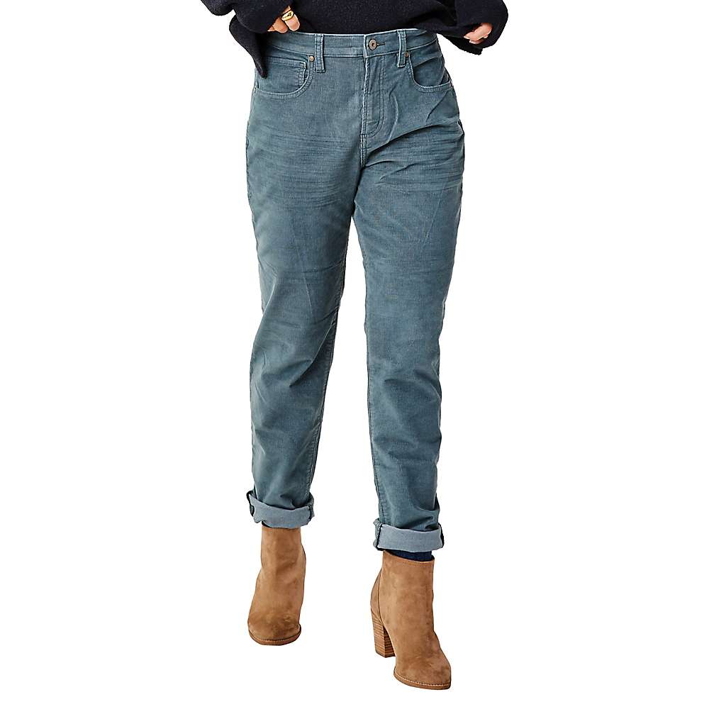 A person wears Carve Designs Women's Carson Cord Hi Rise Pant with rolled cuffs, a black sweater, and tan suede heeled ankle boots, standing against a white background.