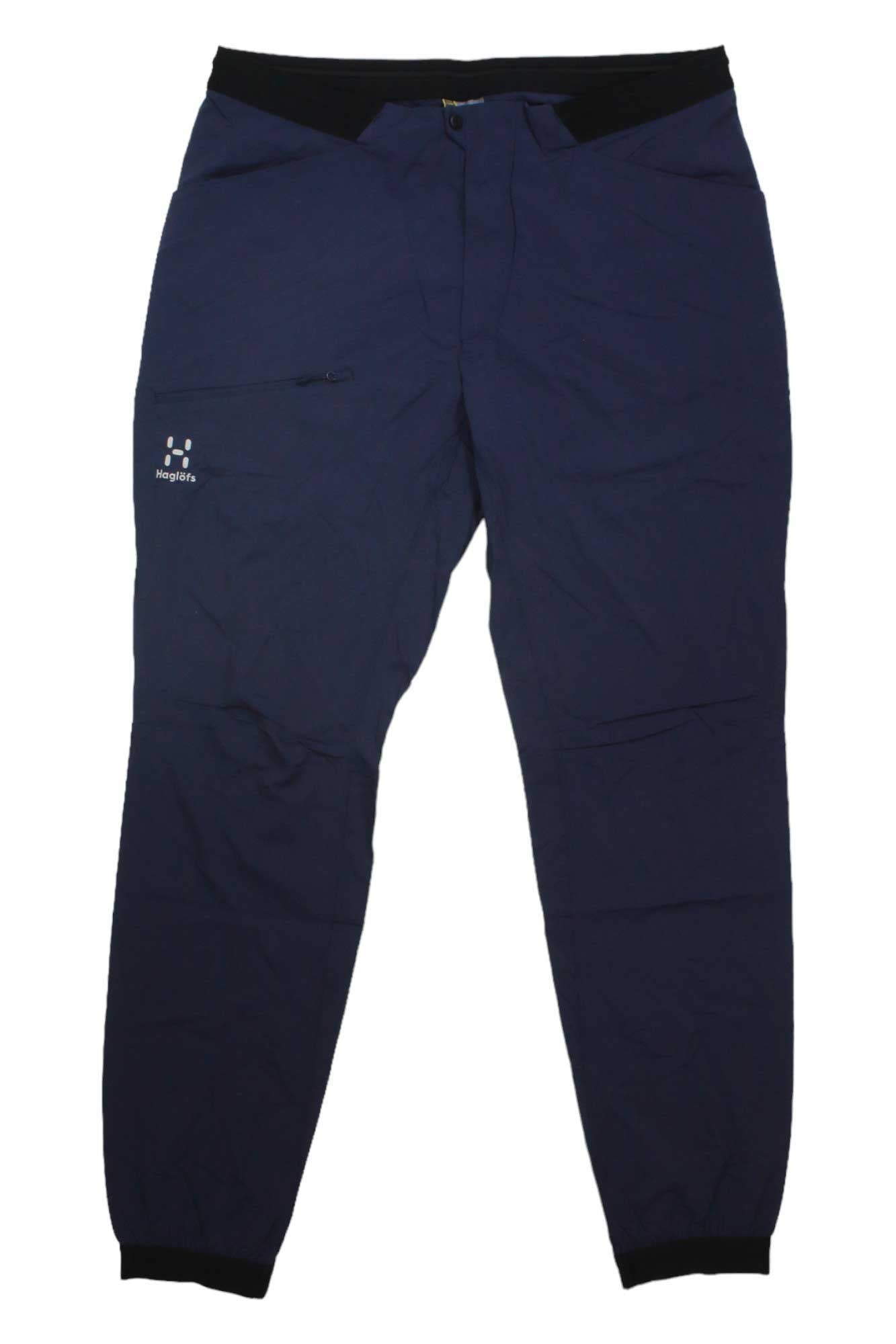 The Haglofs Mens L.I.M Fuse Pant features navy blue quick-drying fabric, a left thigh zipper pocket, elastic ankle cuffs, and a button waist closure—ideal hiking pants for versatility and comfort.