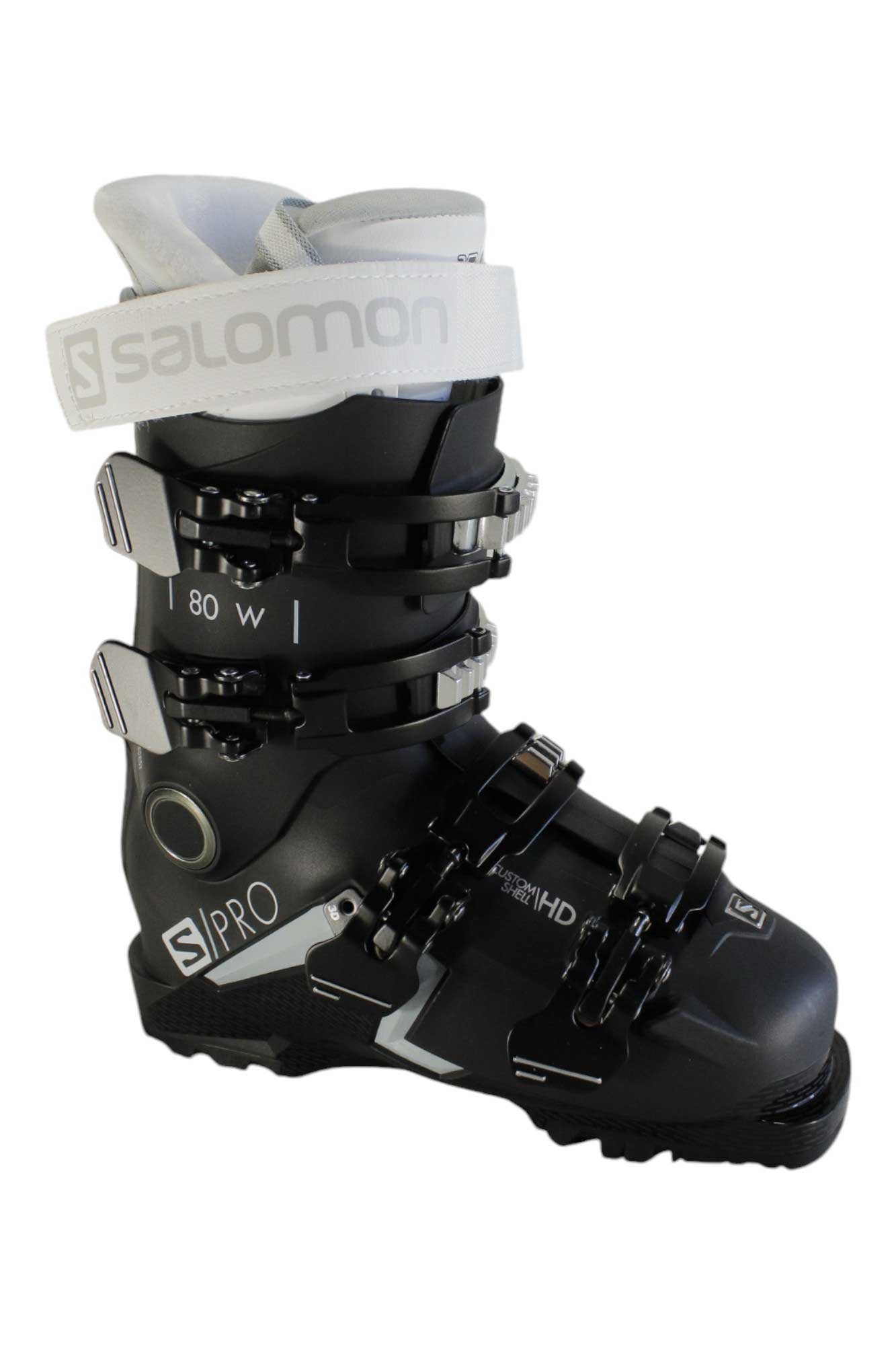 The Salomon S/Pro 80 W CS GW Women's Ski Boots are black with silver buckles, white branding, and a white top strap. Designed for women, they feature custom fit technology and alpine performance labeled S/PRO 80 W.