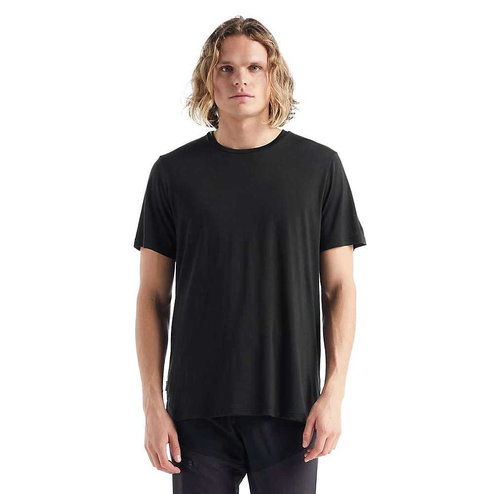 A person with shoulder-length wavy hair wears the Icebreaker Mens Sphere II SS Tee in black and dark pants, standing against a white background and facing forward with a neutral expression.