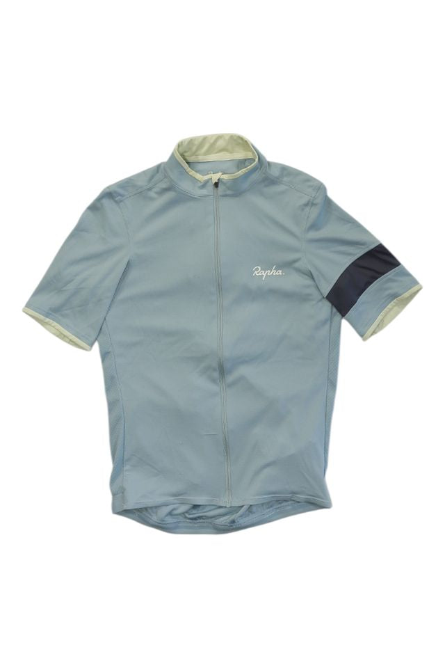The Rapha Mens Super Lightweight Jersey is a light blue short-sleeve cycling top with a front zipper, white Rapha logo on the chest, and a dark navy band on the left sleeve, displayed flat on a white background.