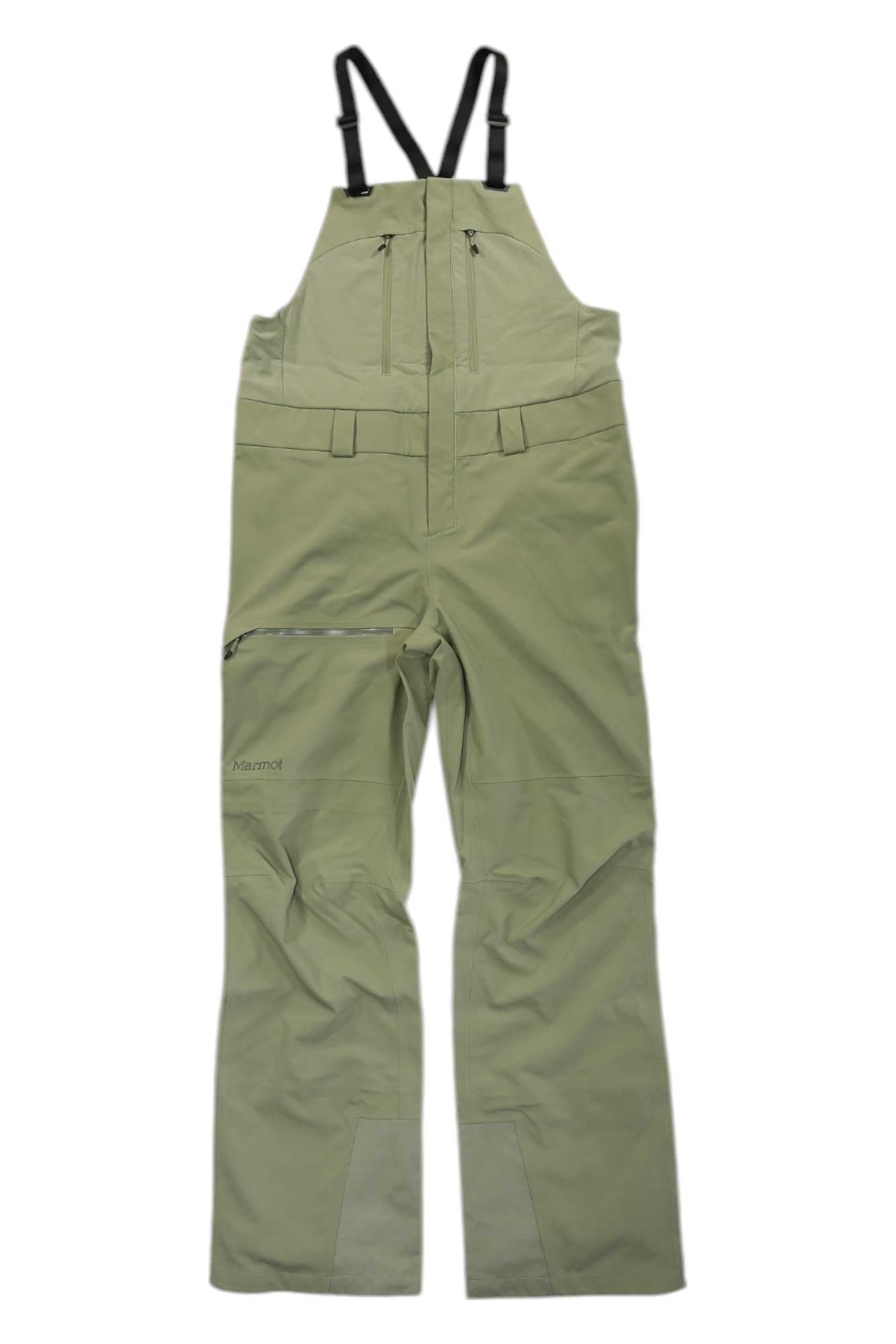 The Marmot Womens Refuge Pro Bib in light green is made from recycled polyester and features waterproof bib pants, black adjustable shoulder straps, zippered chest and side pockets, reinforced cuffs, and a Marmot logo on the left leg.