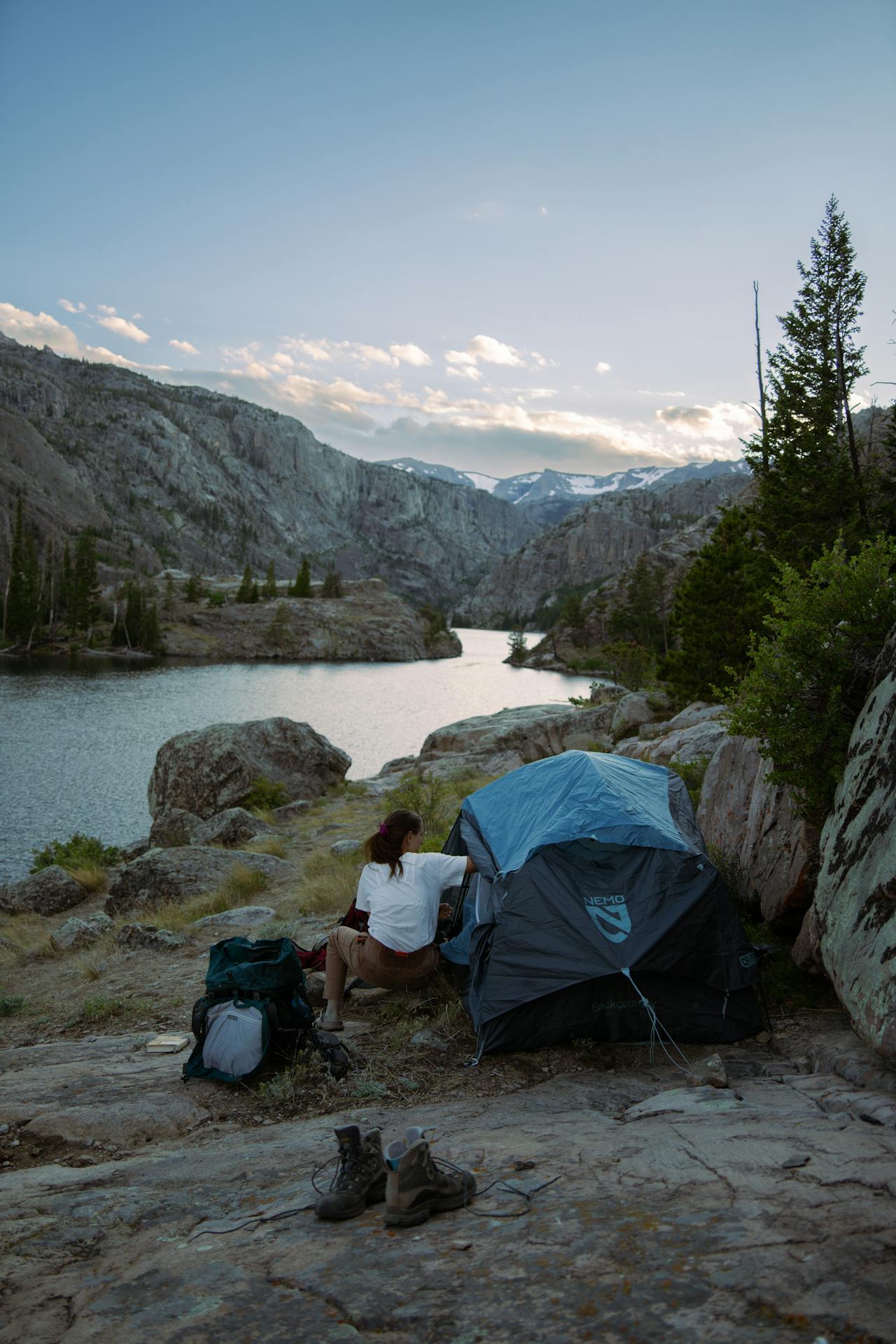 A person opening a tent next to a lake