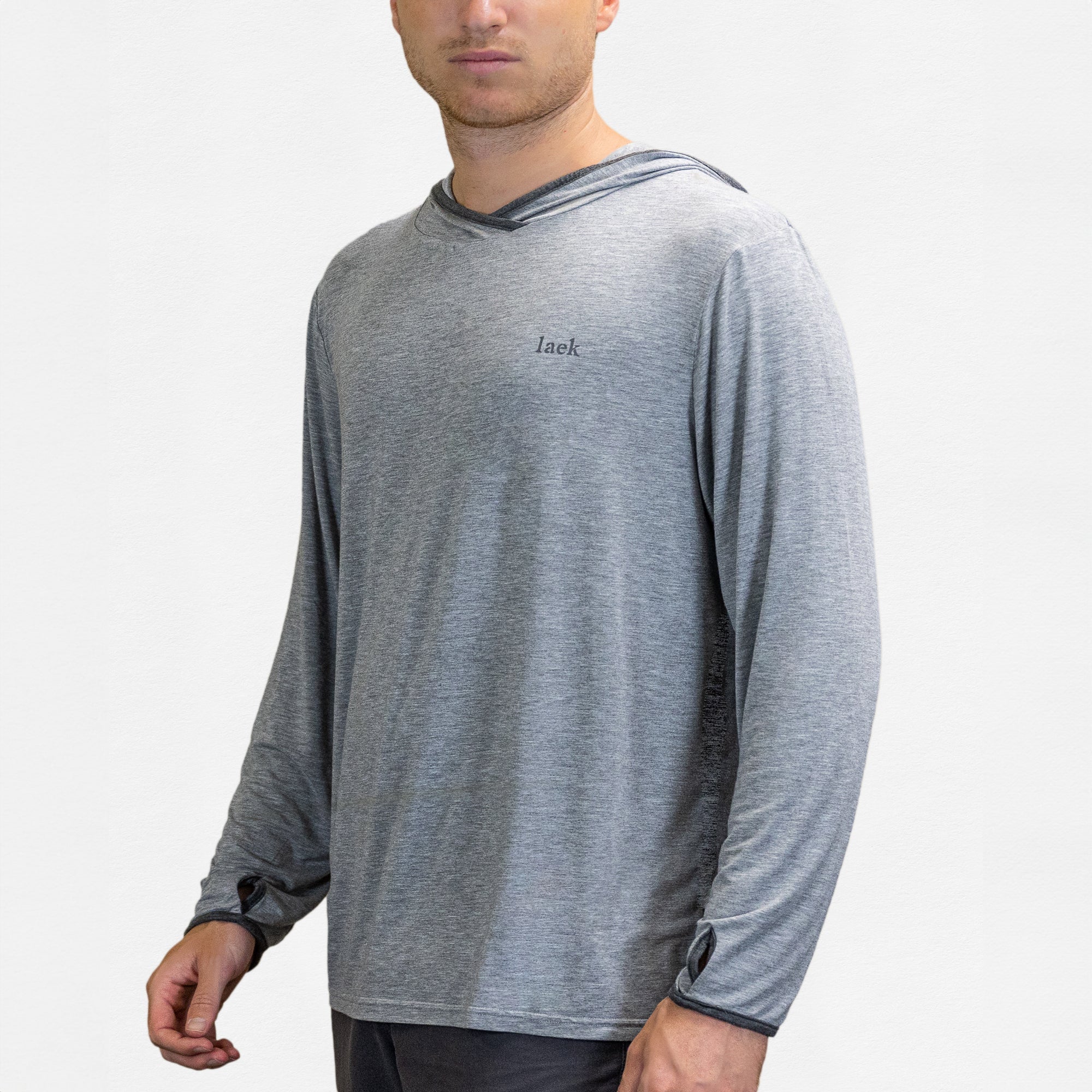 A man wears a light gray Sun Shirt - UV Protective Long Sleeve with Hood, featuring UPF 50, thumbholes, and "laek" printed on the chest, standing against a plain white background.