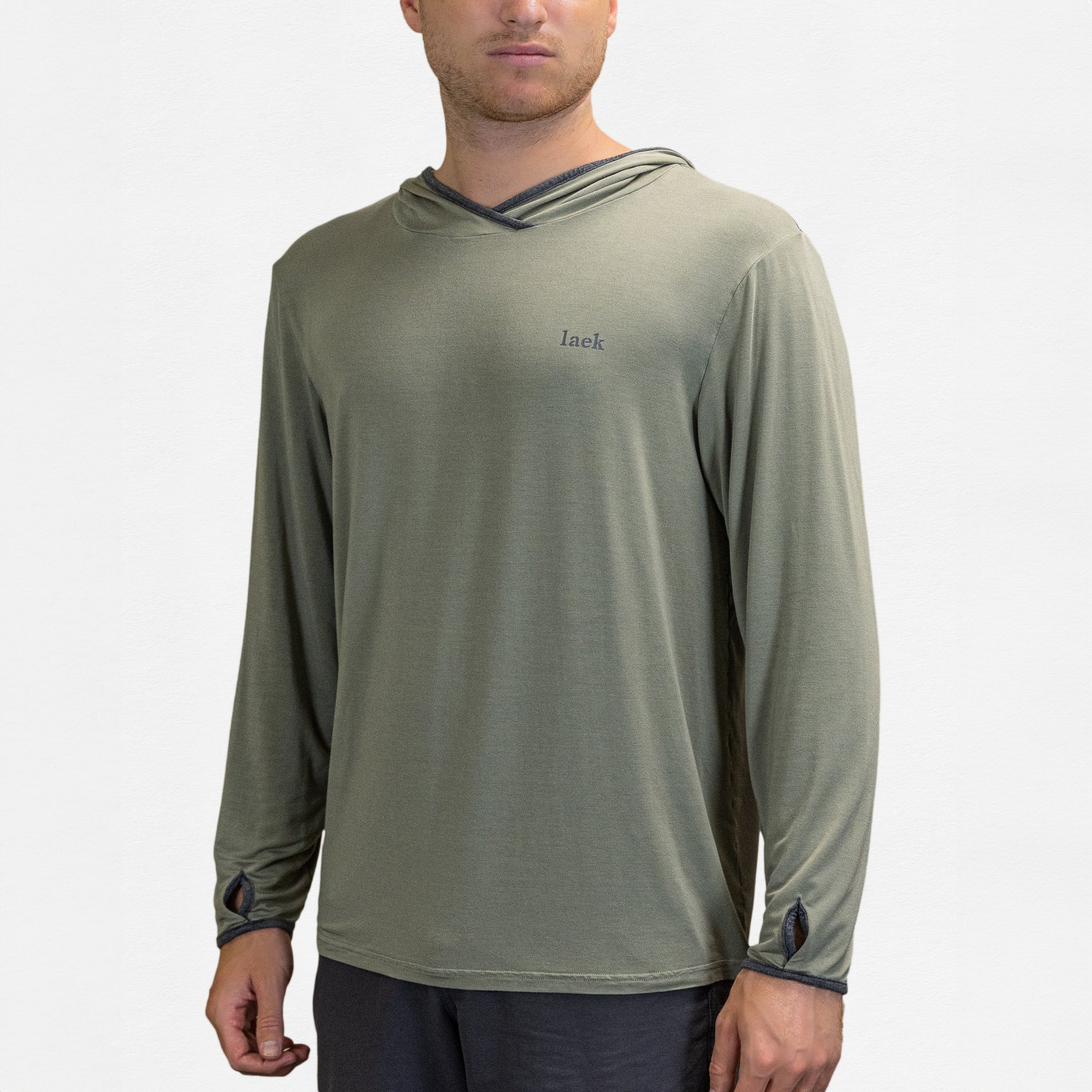 A person wears the Sun Shirt - UV Protective Long Sleeve with Hood in light olive green with thumbholes and dark trim, featuring "laek" on the chest. The UPF 50 shirt provides outdoor sun protection against a plain white background.