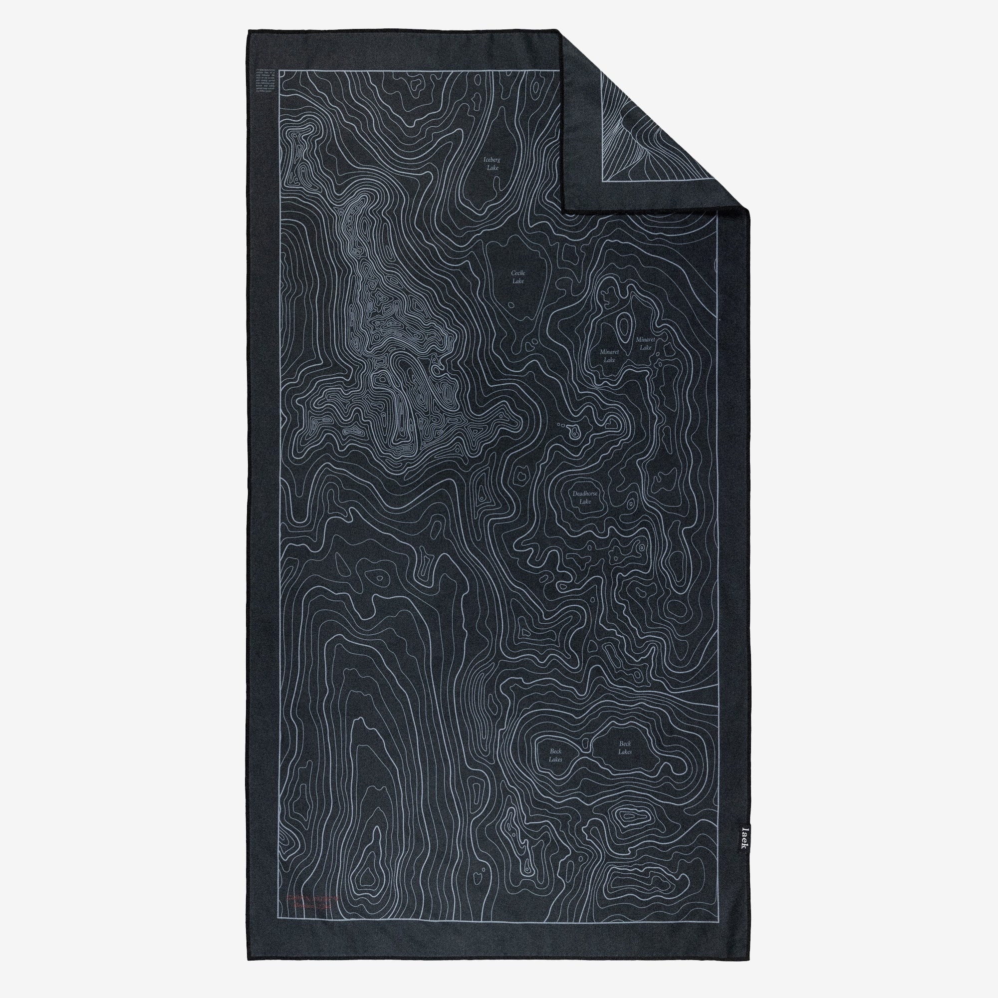 The Adventure Towel is a black rectangular quick-dry towel featuring a detailed contour map design with thin, light lines showing elevation. One corner of the towel is slightly folded over.