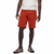 A person stands against a white background, wearing a light gray T-shirt, Men's Notion Shorts in bright orange from Black Diamond made with organic cotton, and gray sneakers with black soles. The image is cropped at the neck.