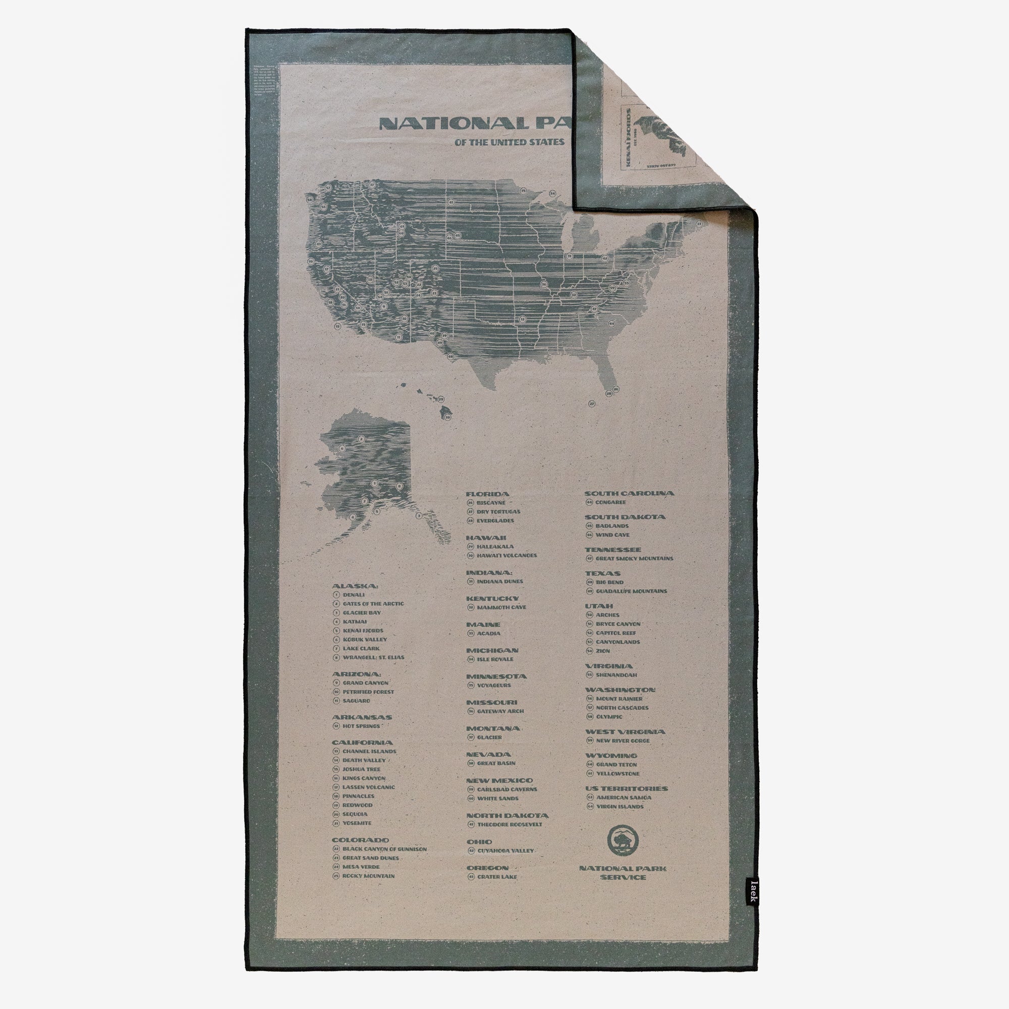 The Adventure Towel is a microfiber, quick-dry towel featuring a US map—including Alaska—and a list of National Parks by state. A folded corner displays the reverse side and showcases its unique design.