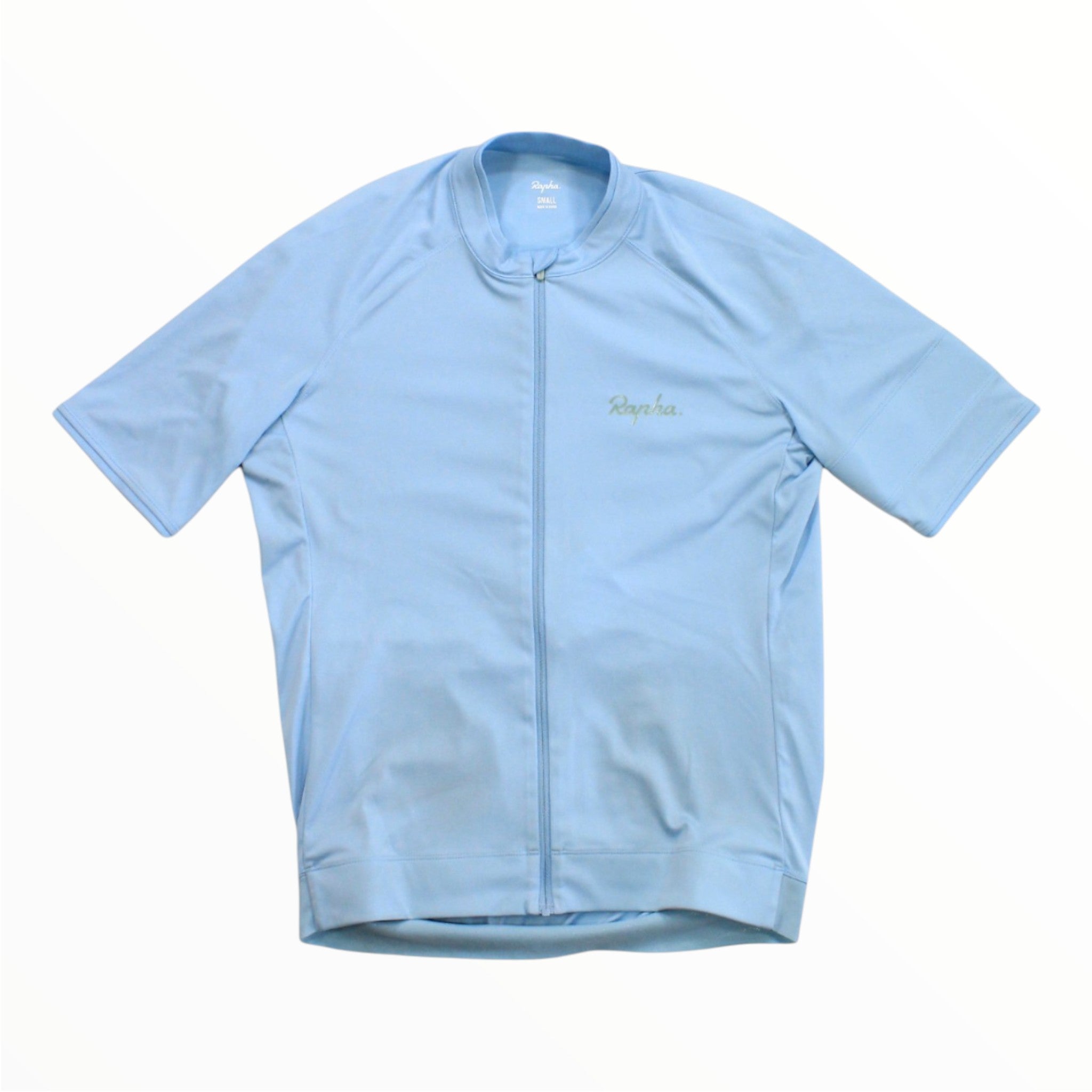 Laid flat on a white background, the Rapha Men’s Core Jersey in light blue features short sleeves, a full front zipper, and the Rapha logo on the left chest.