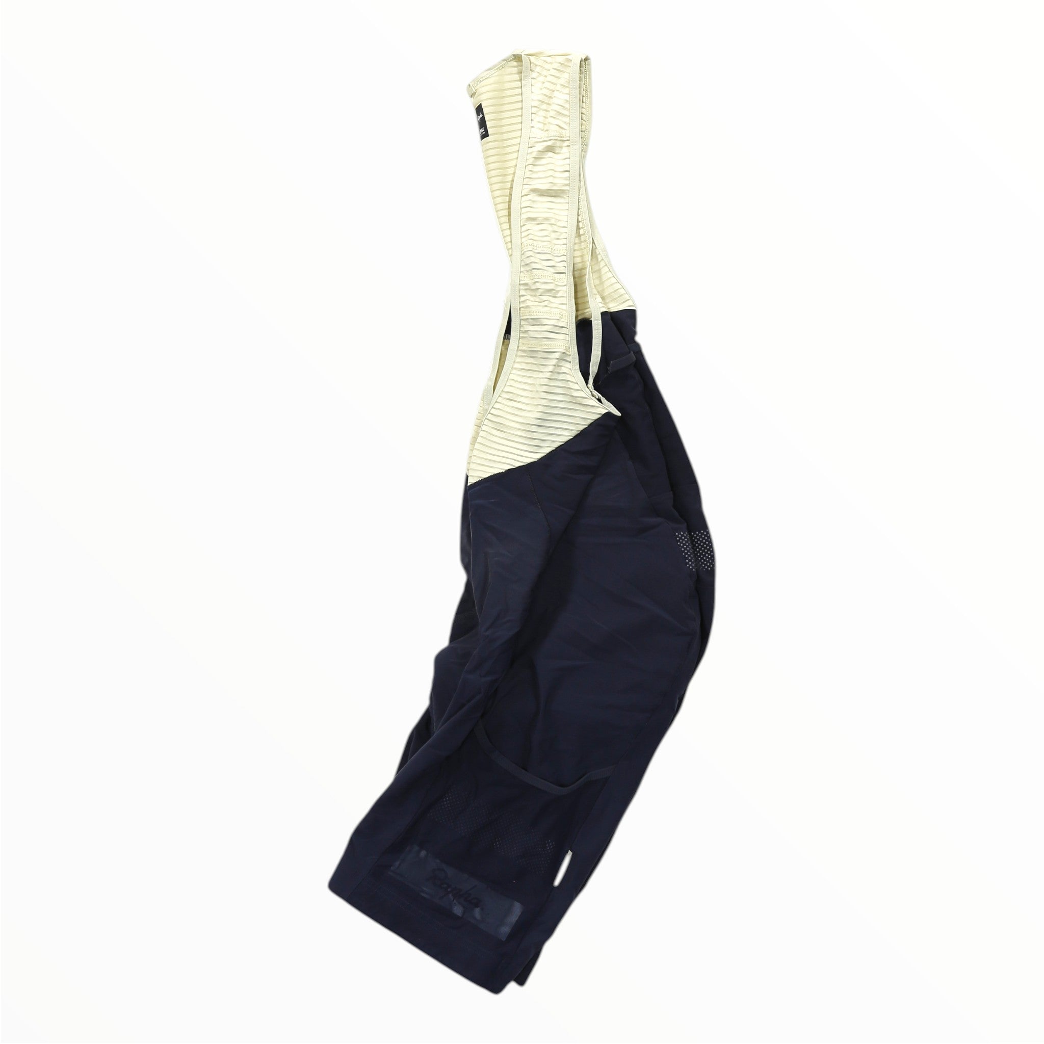 The Rapha Mens Cargo Bib Shorts by Rapha are showcased on a white background, photographed from the side to highlight the contrast between the beige shoulder straps and the black shorts. Designed in the style of premium cycling bibs, they feature chamois padding for optimal comfort during long rides.