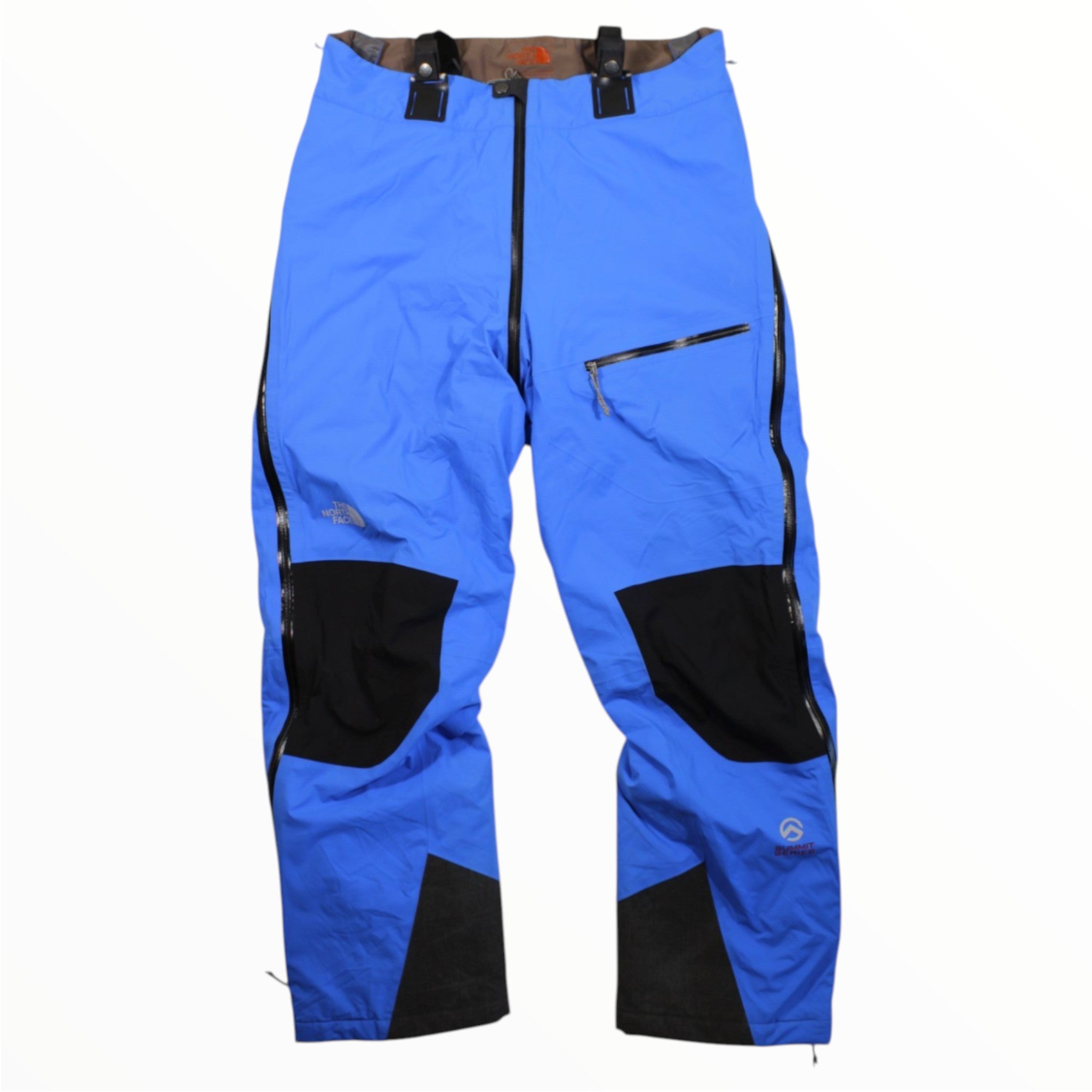 The North Face Mens Himalayan Summit Series Expedition Pant in bright blue features black reinforced knees and ankles, zippered side vents, and a horizontal-zip front pocket—designed for mountain protection and shown flat on a white background.