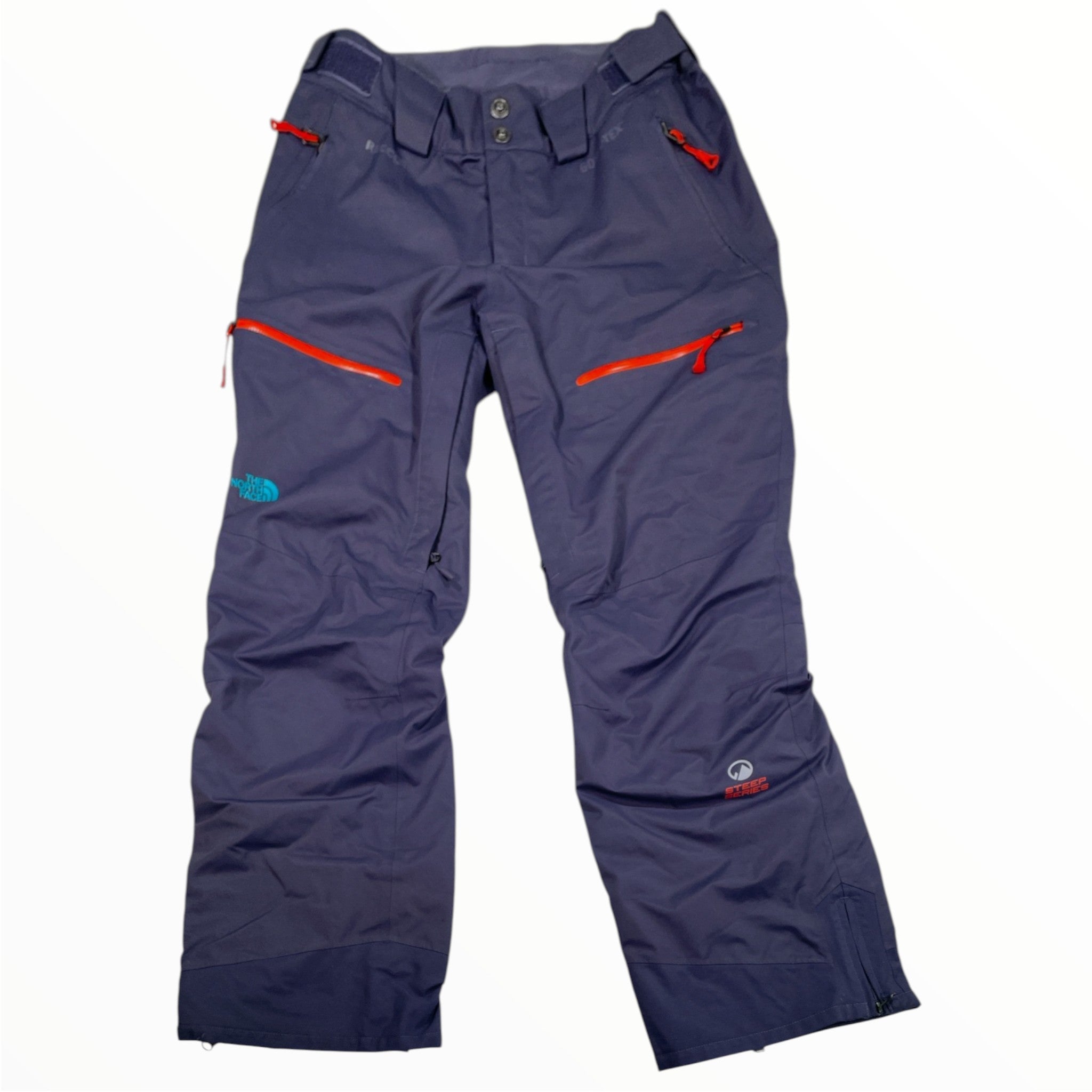 The Women's Purist Snow Pants by North Face are dark blue with red zipper pockets, button and zipper closure, belt loops, Gore-Tex branding on the lower leg, and a chimney venting system for breathability.