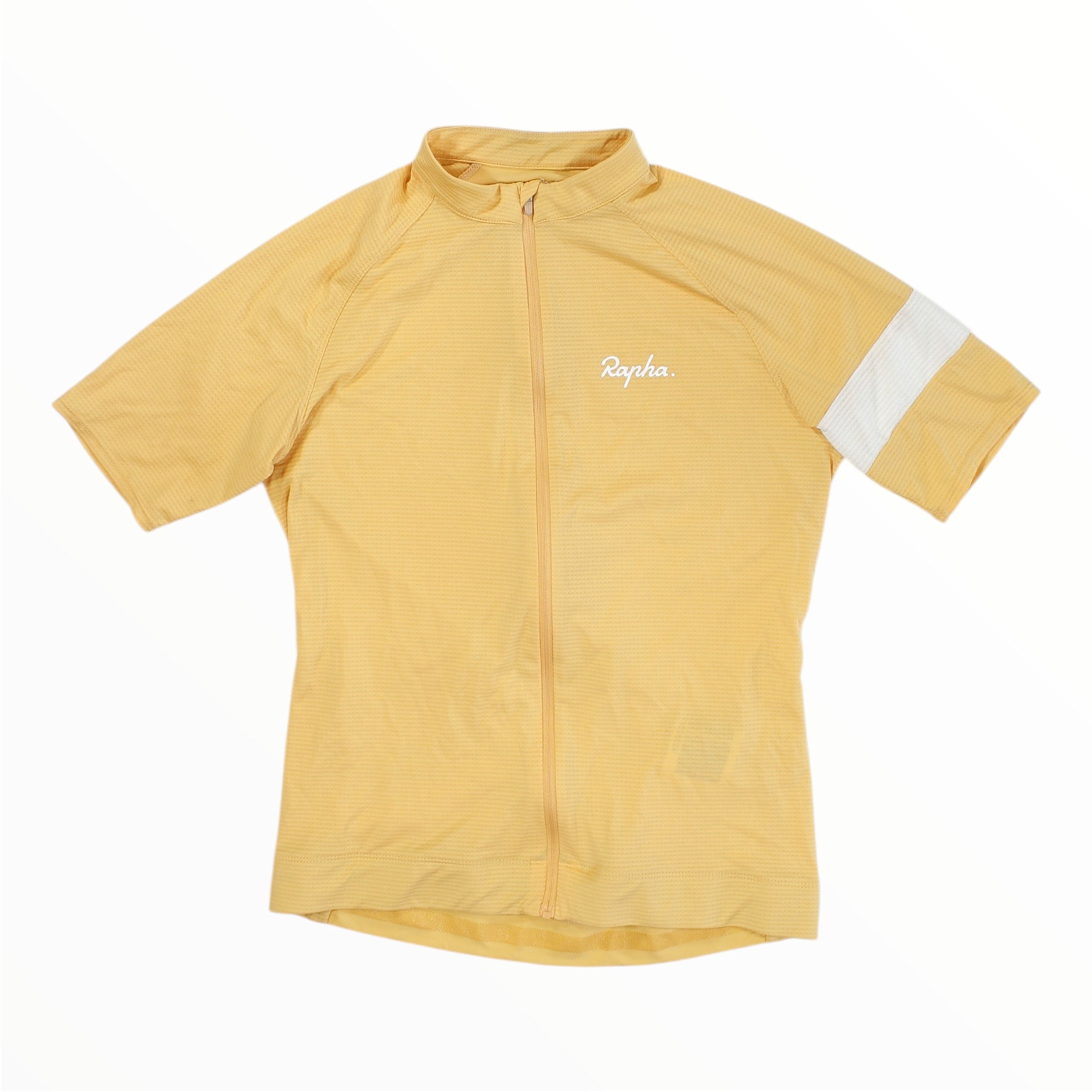 A Rapha Mens Core Jersey in light yellow, featuring short sleeves, a front zipper, a white Rapha logo on the chest, and a bold white stripe encircling one sleeve, is laid flat against a white background—a standout cycling jersey from Rapha.