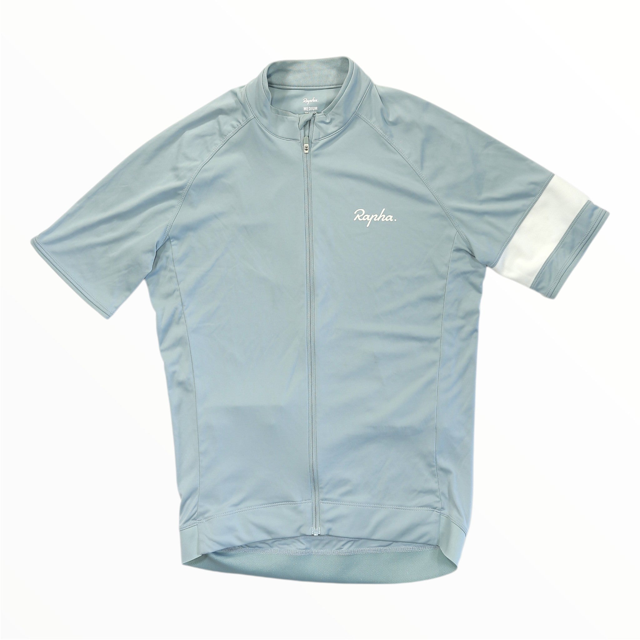 The Rapha Mens Core Jersey by Rapha is a light blue short-sleeve cycling jersey with a full front zipper, showcasing a white Rapha logo on the left chest and a white band on the left sleeve. Laid flat against a white background, this stylish essential is designed for men’s cycling apparel.