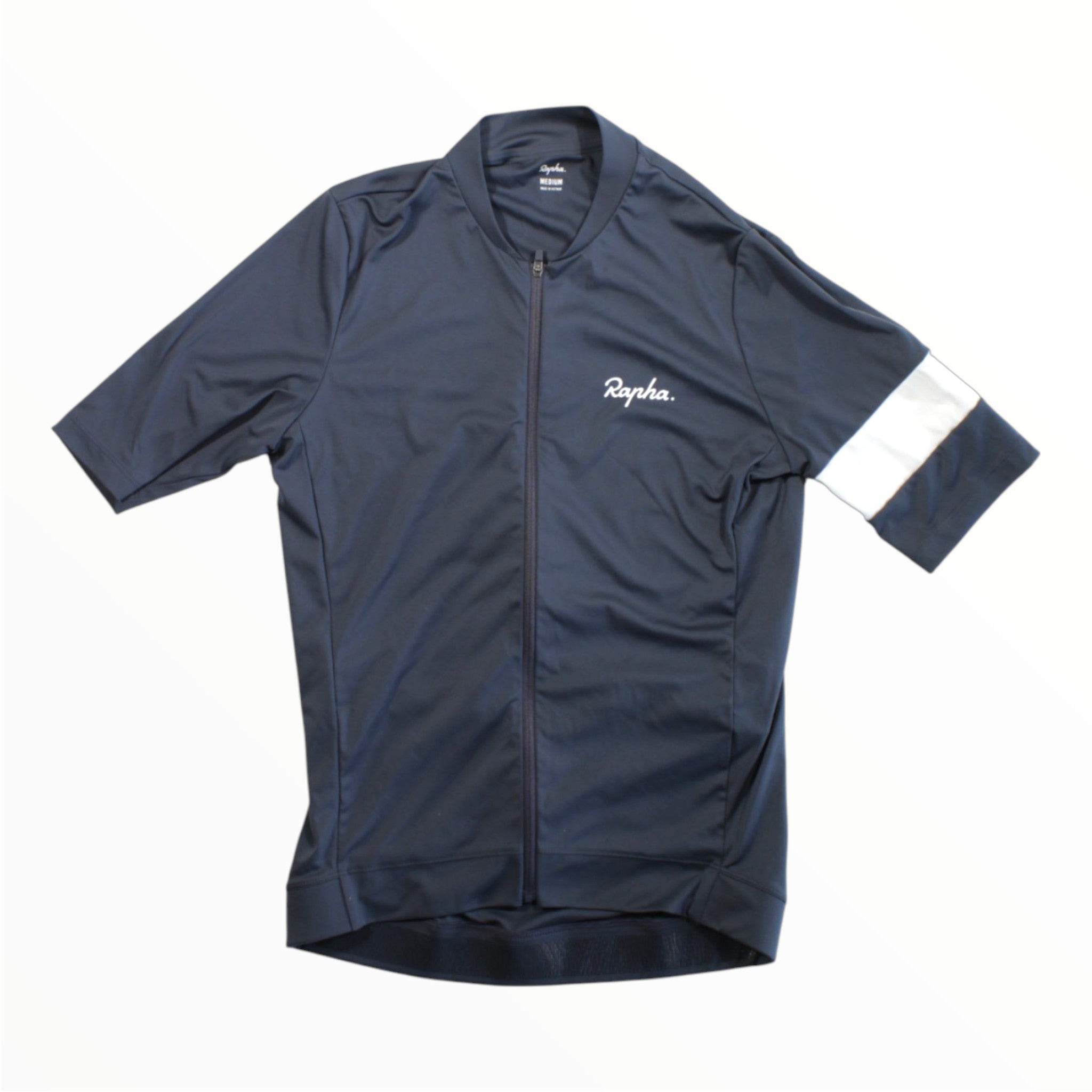 A Rapha Mens Core Jersey in navy is displayed flat on a white background. This short-sleeved cycling jersey features a white Rapha logo on the chest and a distinctive white stripe around the left sleeve, blending essential style and performance for every ride.
