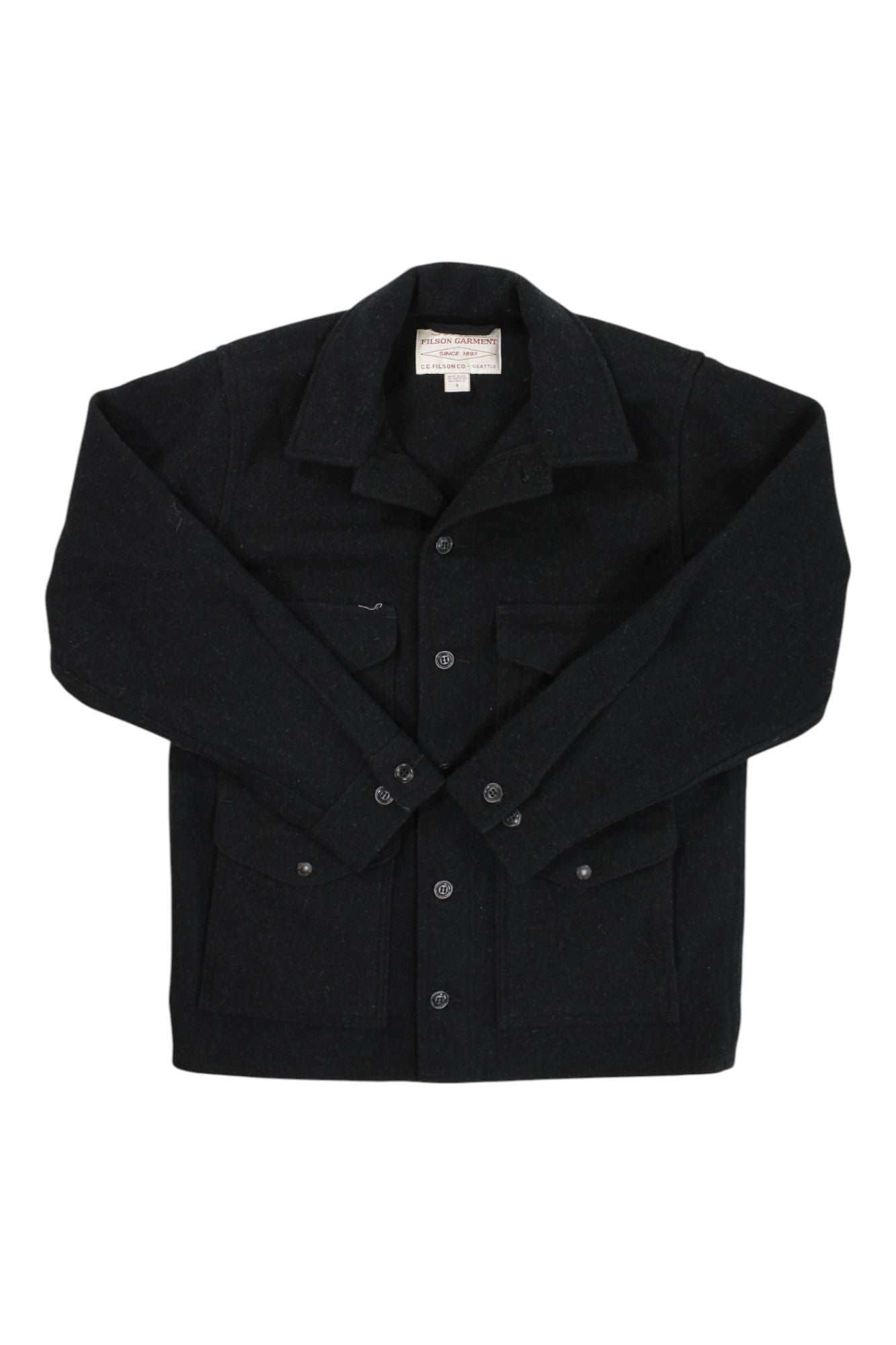 The Filson Mens Mackinaw Cruiser Jacket is a black wool jacket inspired by the classic design, featuring a collar, front buttons, long sleeves, and two chest pockets, shown flat on a white background.