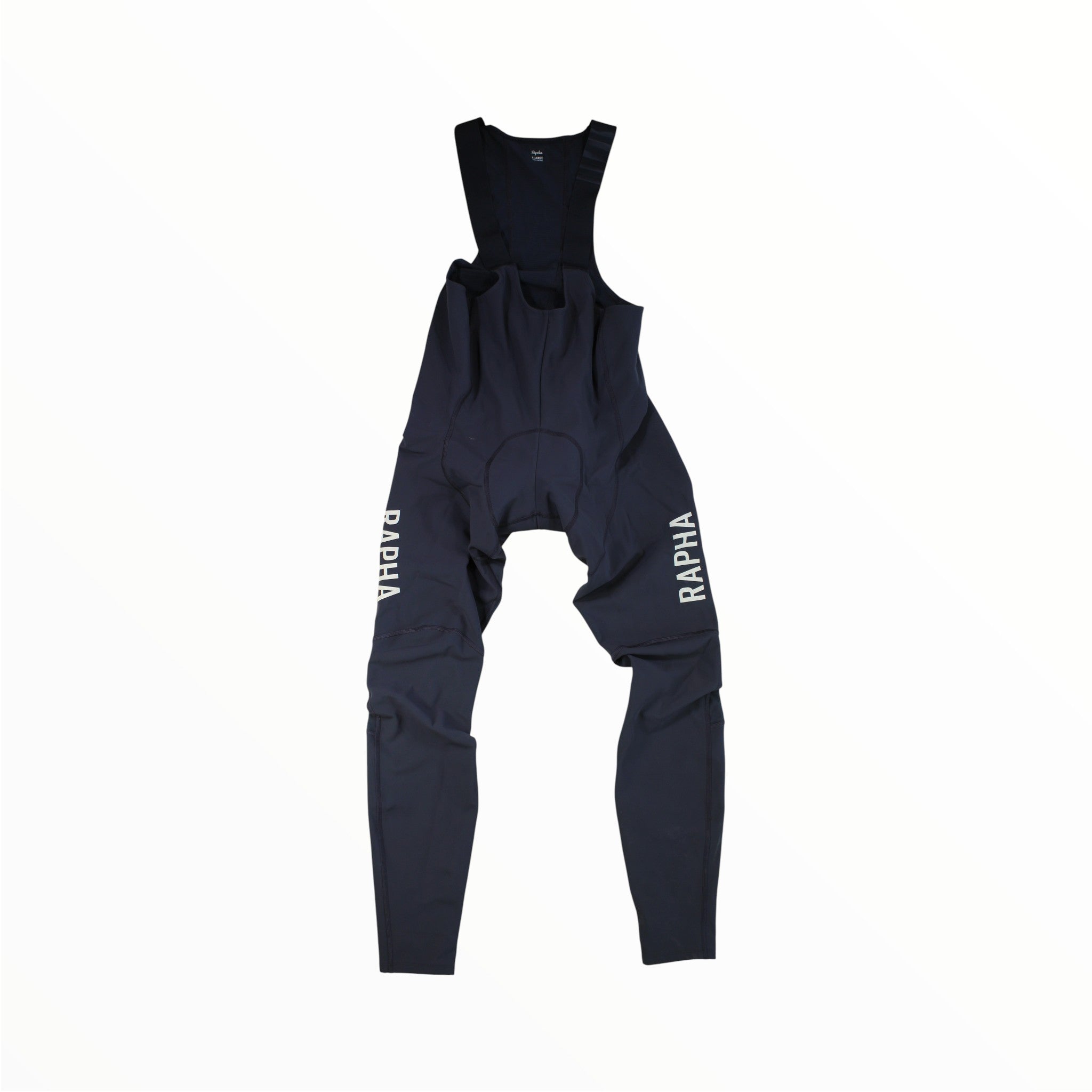 A pair of Rapha Men’s Pro Team Winter Tights with Pad II in navy blue, featuring white RAPHA logos on each leg, are laid flat against a plain white background, highlighting premium wind-blocking cycling apparel engineered by Rapha for comfort and performance during long winter rides.