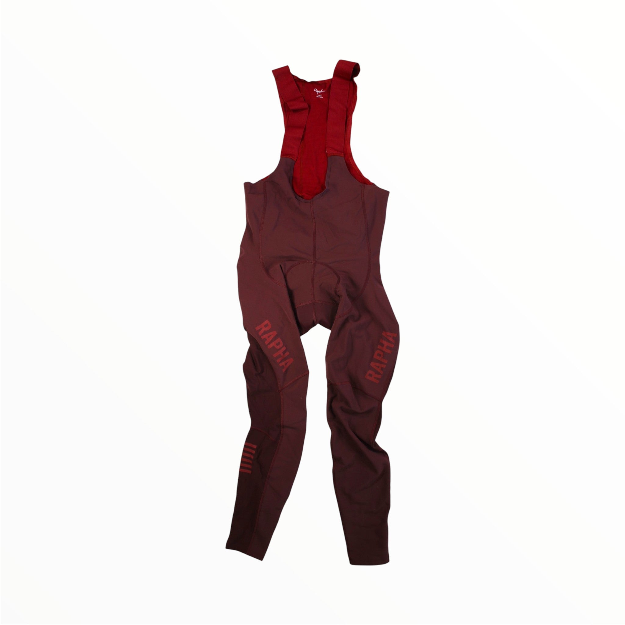 The Rapha Men’s Pro Team Winter Tights with Pad II, featuring shoulder straps and RAPHA branding on the left leg, are displayed against a plain white background. These maroon bib tights are specifically designed by Rapha for men, providing padded comfort and high performance during cold weather rides, making them an essential piece for any cyclist’s wardrobe.