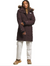 A person stands facing forward, one hand by their side and the other partly tucked in their sleeve, wearing The North Face Womens Arctic Parka—long, dark brown with a fur-lined hood—paired with light pants and tan boots.