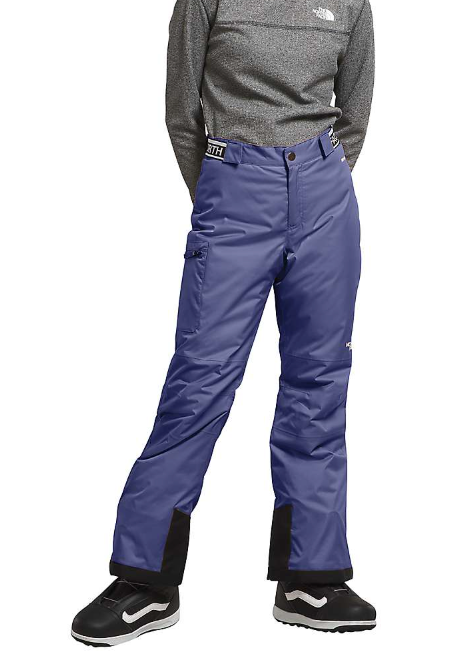 A person in a grey long-sleeve top, The North Face Girls Freedom Insulated Pant, and black and white winter boots stands with hands behind their back.