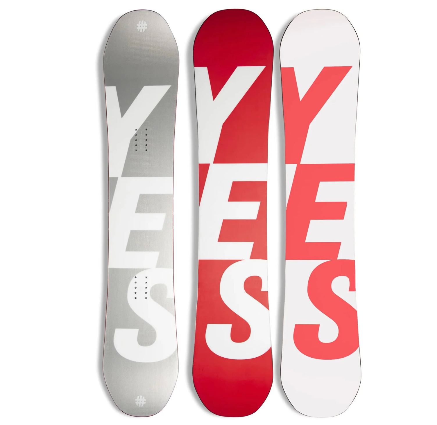 Three YES Basic Snowboard 26 models are displayed upright, each showcasing bold, modern graphics with overlapping red, white, and gray letters that spell YEESS.
