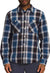 A person is shown from the waist up wearing the Mens Valley Twill Flannel Shirt in blue, black, and white organic cotton with two chest pockets, paired with dark-colored pants.