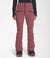 A person faces forward against a plain white background wearing Womens Amry Soft Shell Pants in a pinkish-red shade with black zippers, paired with a black long-sleeve top and black boots.
