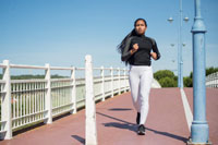 a woman jogs on a concrete footpath