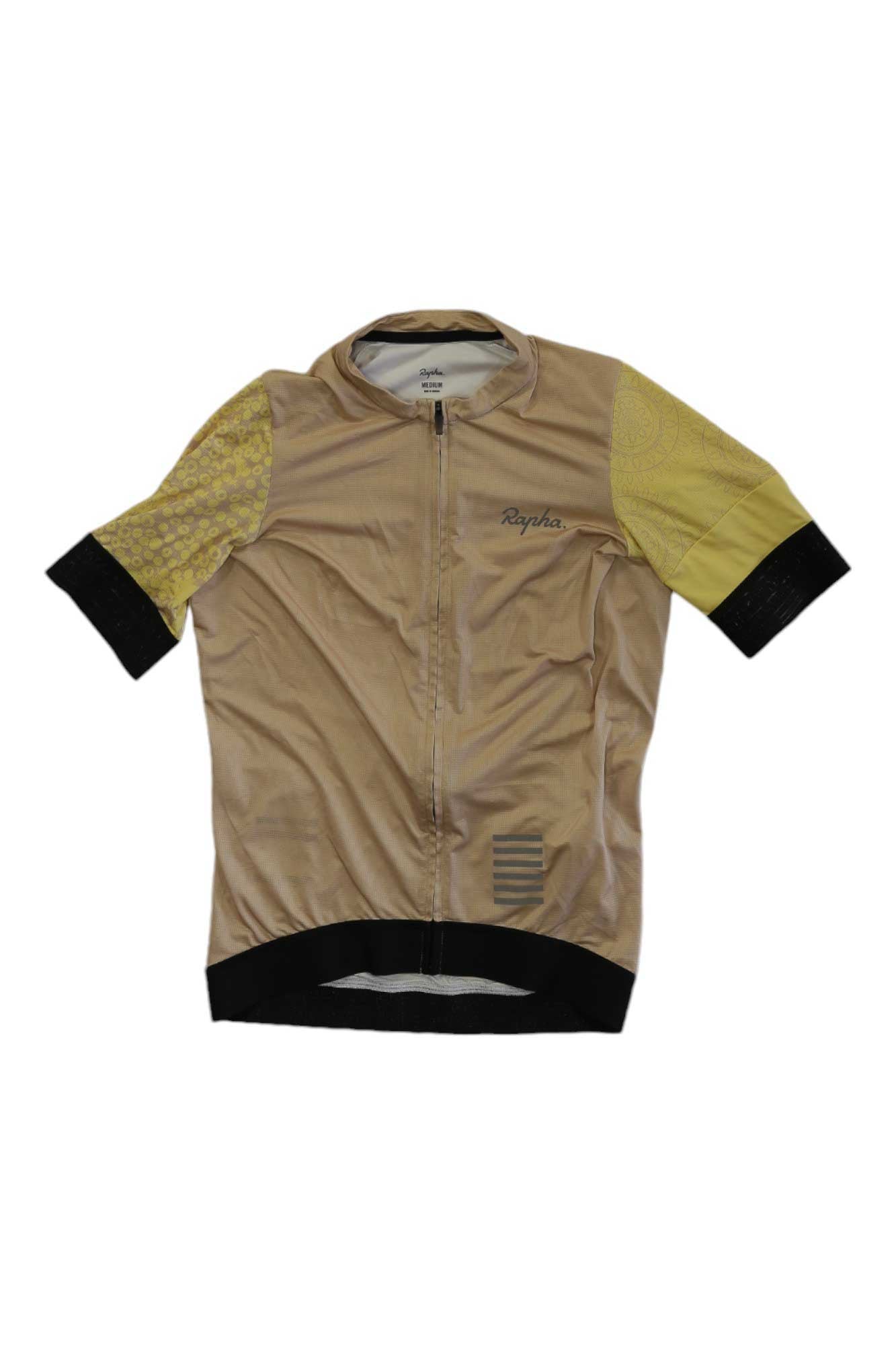 The Rapha Pro Team Training Jersey is a high-performance cycling top with short sleeves, front zipper, beige and black accents, one yellow sleeve, and Rapha branding on the chest.