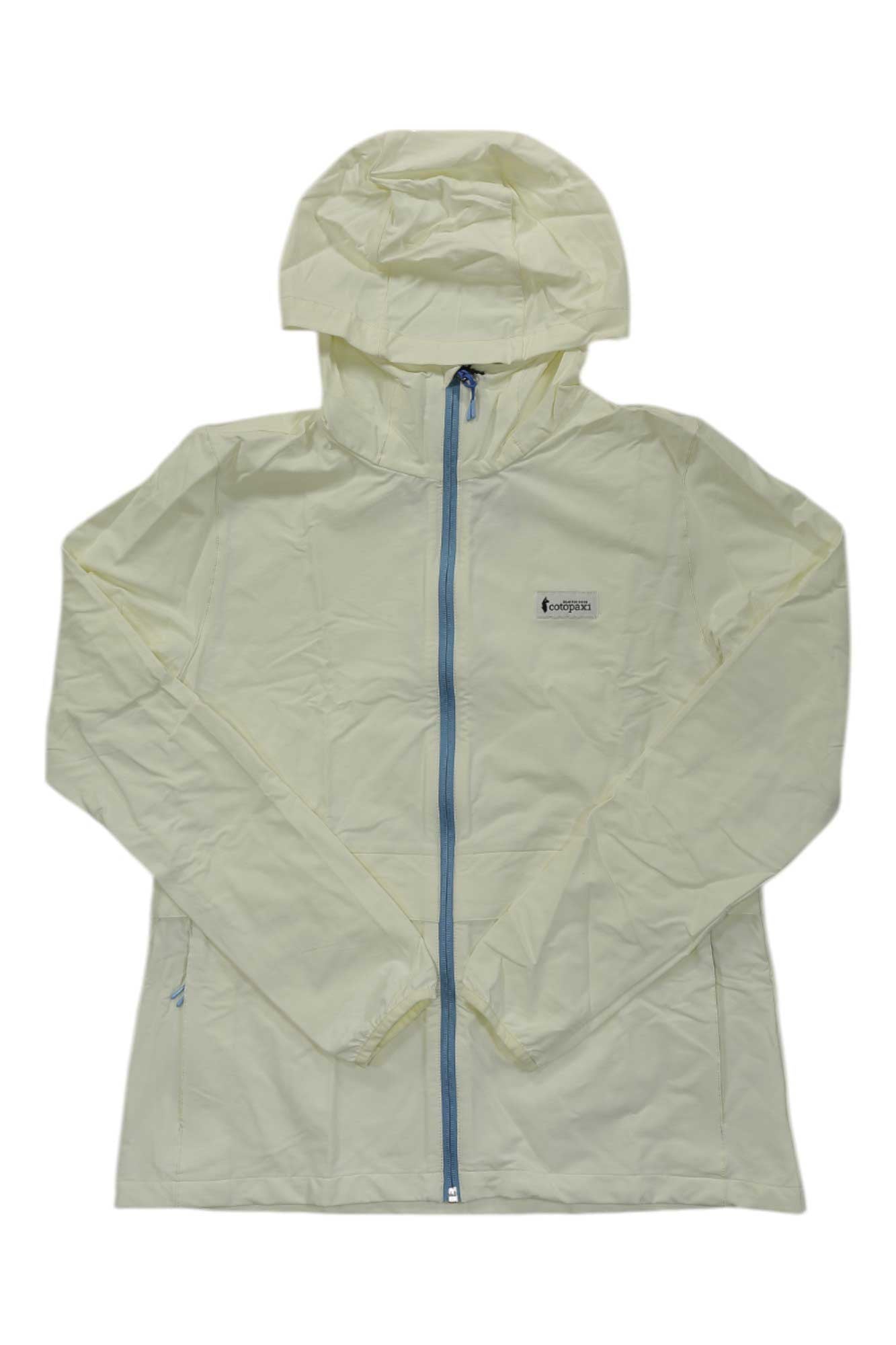 The Cotopaxi Womens Viento Travel Jacket is a light yellow, hooded jacket with a front zipper, long sleeves, side pockets, and a small logo patch on the left chest—ideal for travel and daily wear.