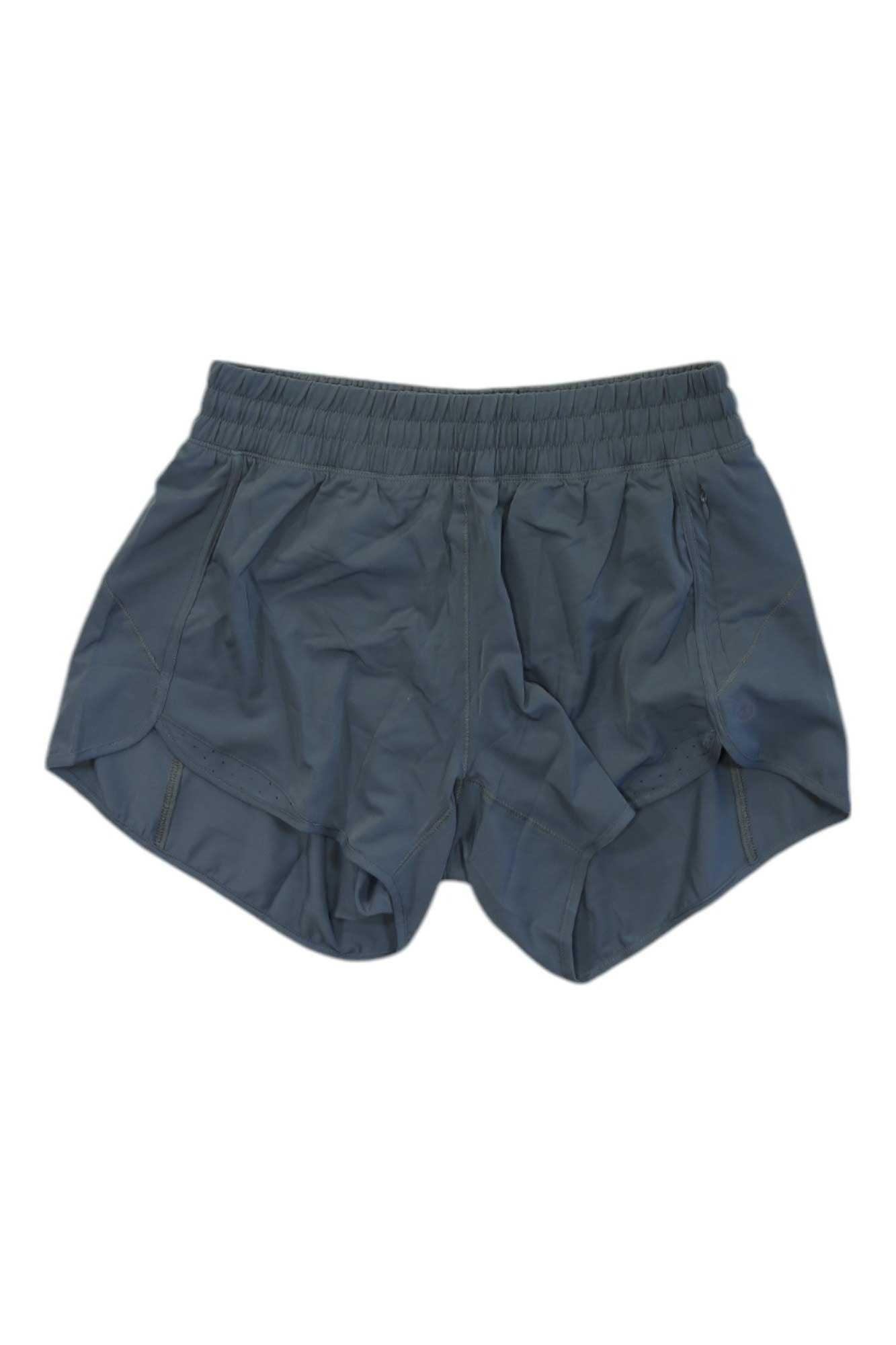 The Tasc Womens Recess 4 Inch Athletic Short in dark gray features an elastic waistband and curved side hems, shown laid flat on a white background.