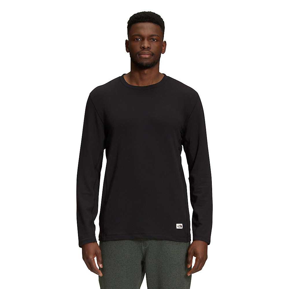 A man stands facing forward, wearing The North Face Mens Terry Crew in black and dark green pants against a white background.