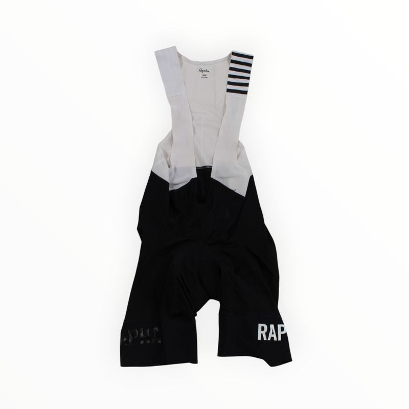 A pair of black and white Rapha Mens Pro Team Bib Shorts II - Regular with shoulder straps, race-grade chamois, RAPHA printed in white on the lower right leg, and horizontal stripes on one strap.