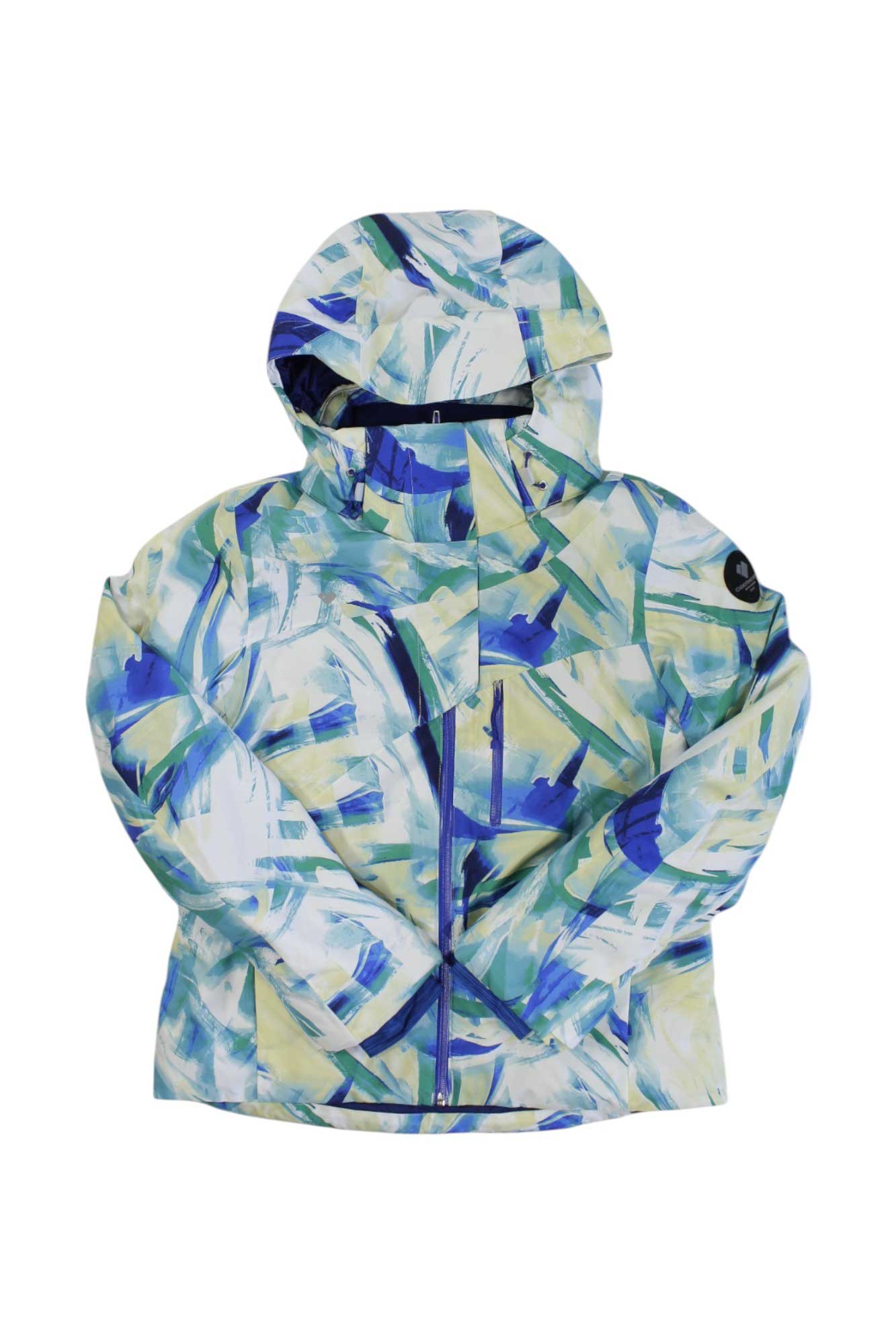 The Obermeyer Womens Jette Jacket is a hooded, insulated ski jacket with a vibrant blue, green, and yellow abstract pattern. It features a front zipper and a logo patch on the left sleeve, displayed against a white background.
