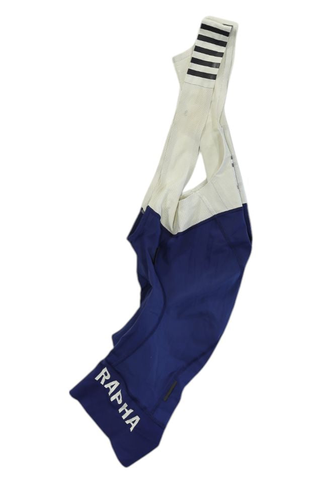 Blue and white Rapha Mens Pro Team Bib Shorts II - Regular with a race-grade chamois, RAPHA in white on the left leg, and black horizontal stripes on one shoulder strap, shown against a white background.