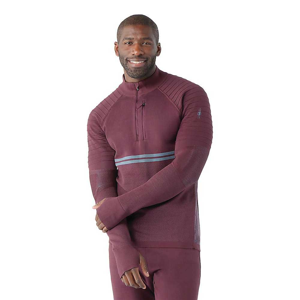 A man smiles at the camera wearing a maroon Smartwool Men's Intraknit Merino Tech 1/4 Zip Top with grey chest stripes and textured sleeves, ideal for high-intensity activities.