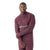 A man smiles at the camera wearing a maroon Smartwool Men's Intraknit Merino Tech 1/4 Zip Top with grey chest stripes and textured sleeves, ideal for high-intensity activities.