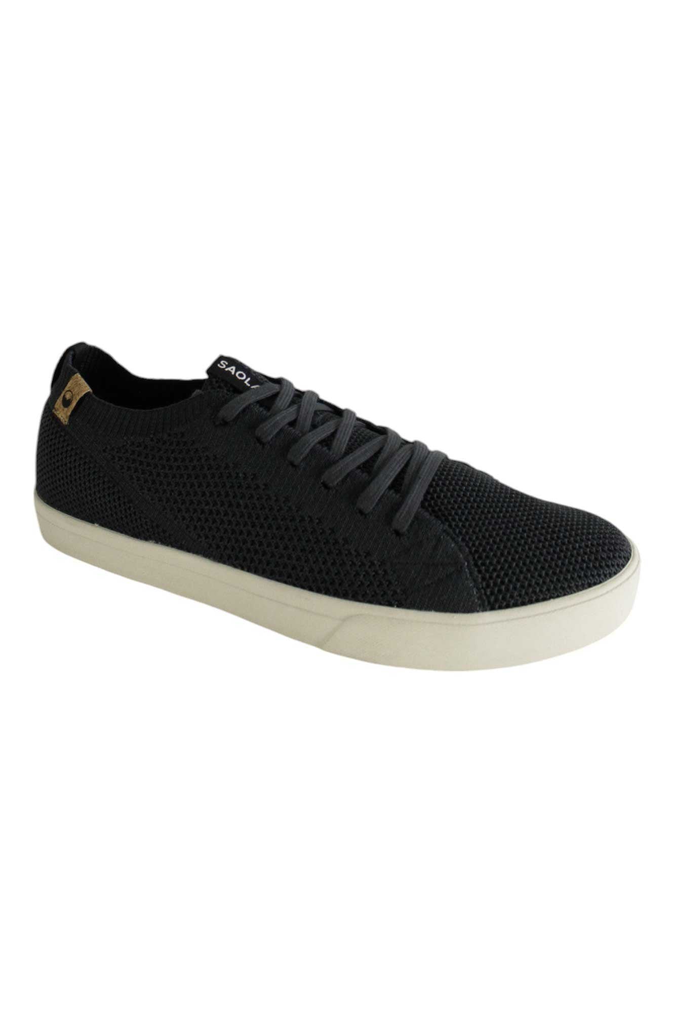 The Saola Women's Cannon Knit Shoe is a black vegan low-top sneaker made from textured mesh, featuring black laces and a white rubber sole, displayed on a white background.
